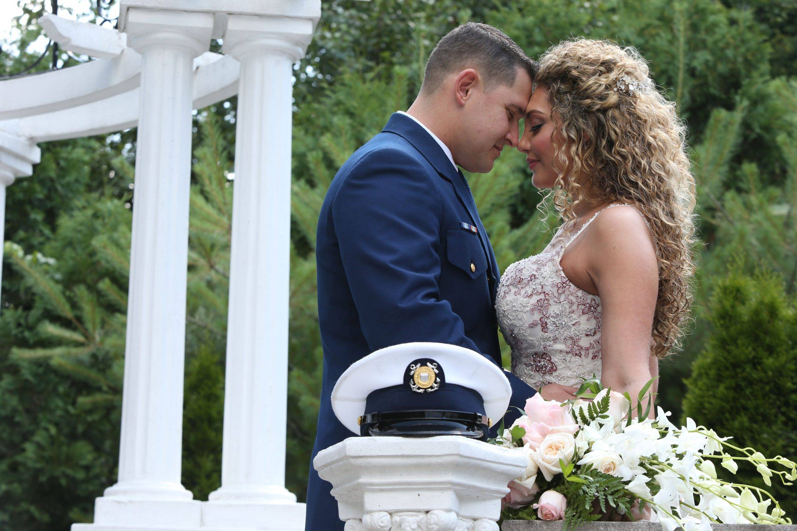 A bride and groom embracing in front of a gazebo.