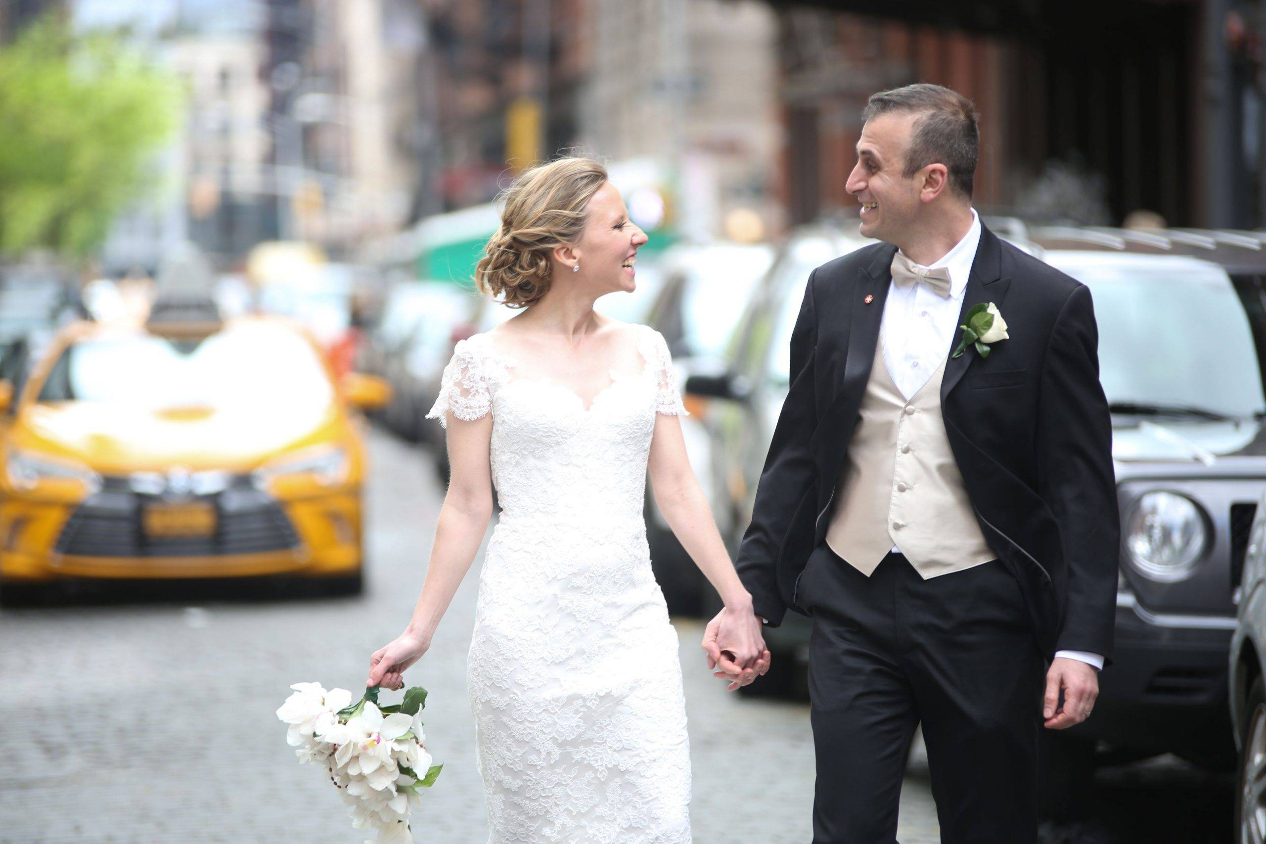 A bride and groom walking down a city street.