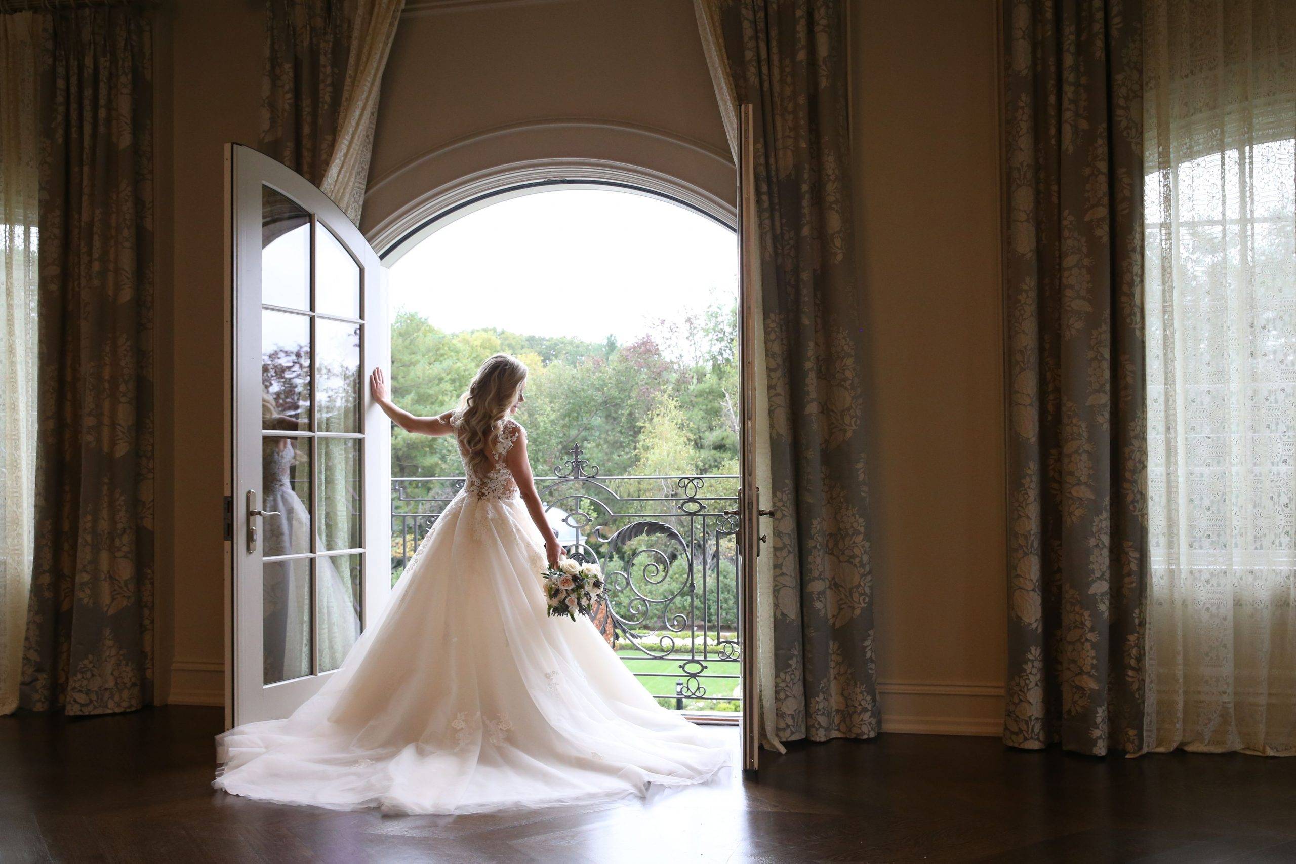 A bride in a wedding dress standing in front of an open door.