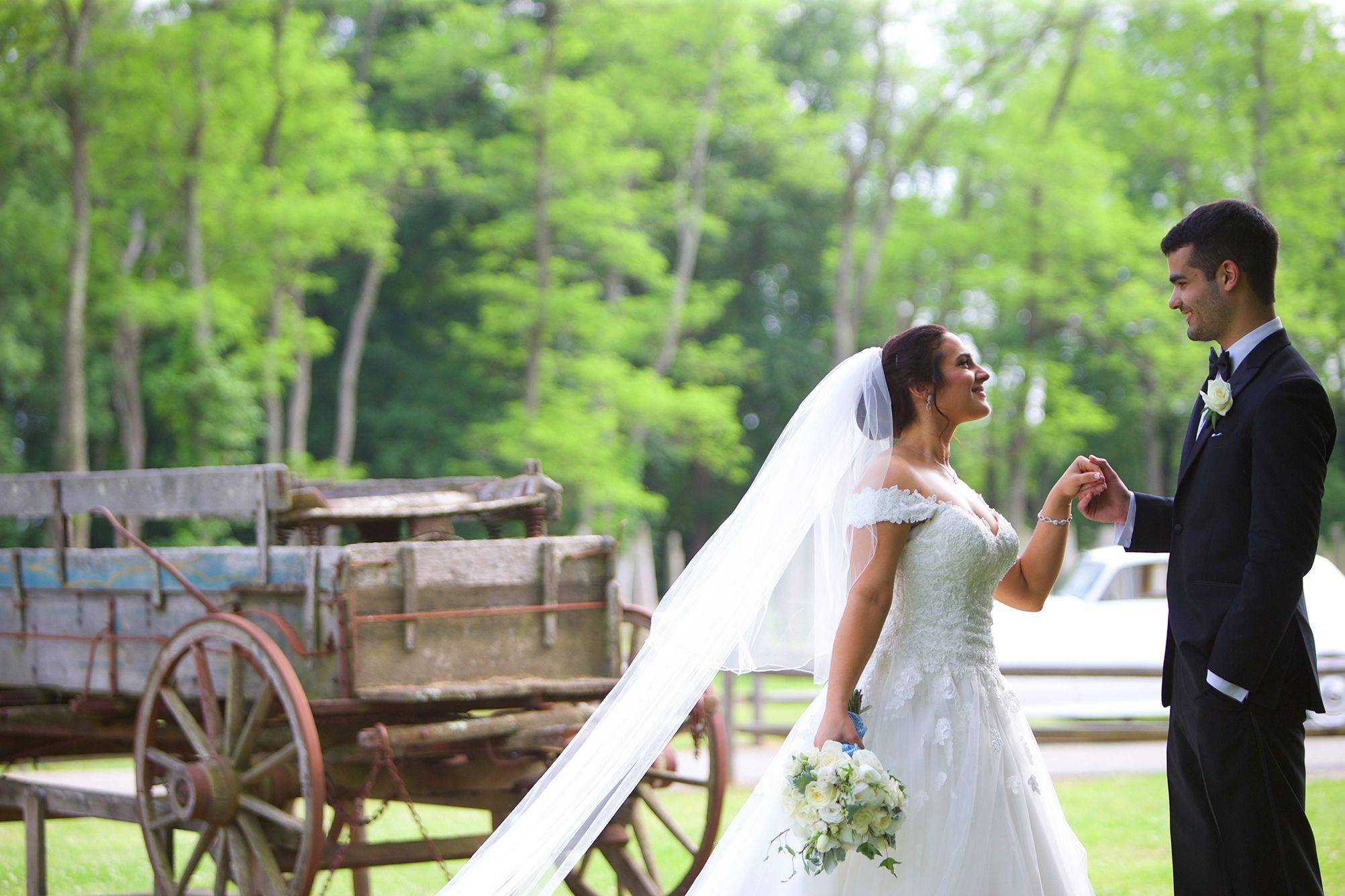 A bride and groom standing in front of a wagon.