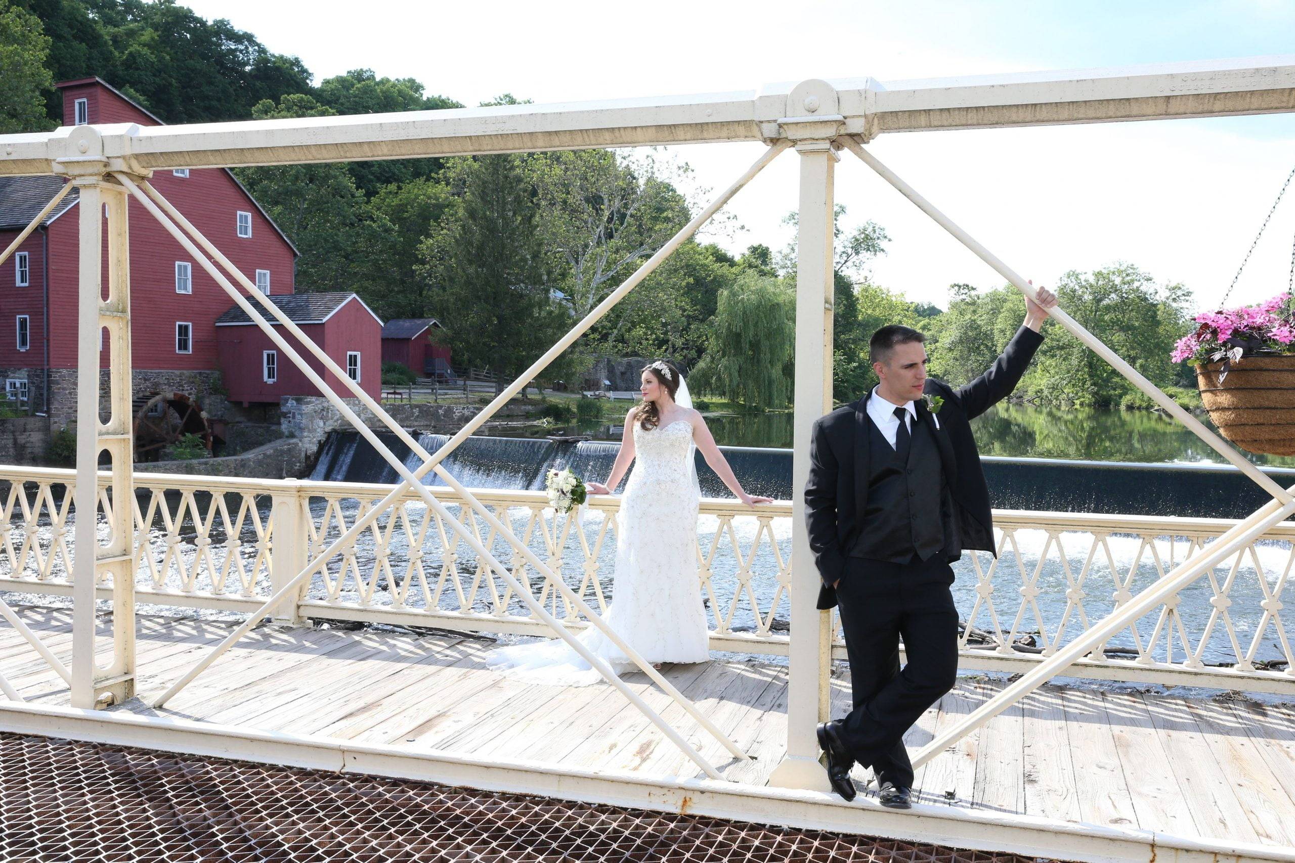 A bride and groom standing on a bridge.