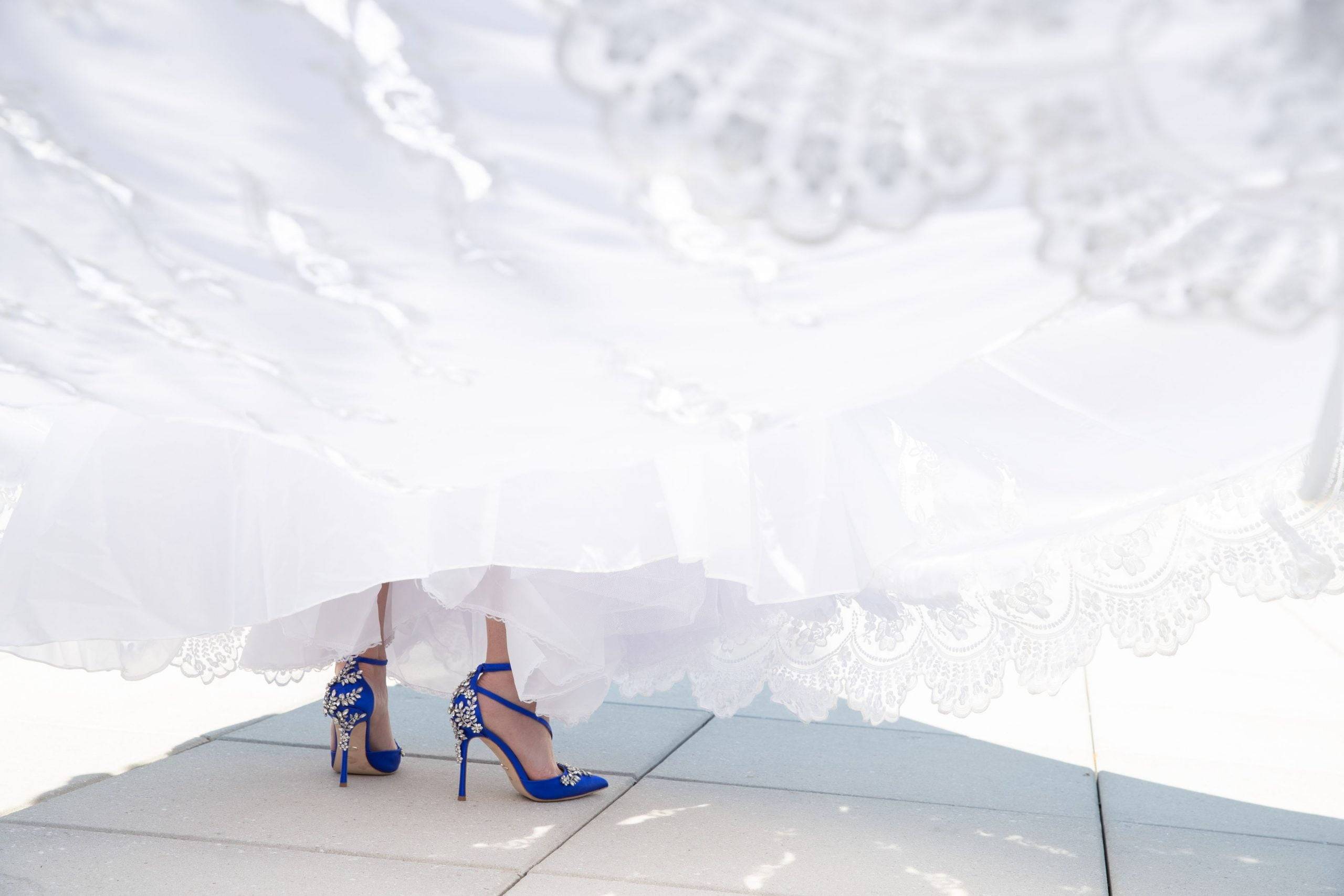 A bride in a white dress with blue heels.