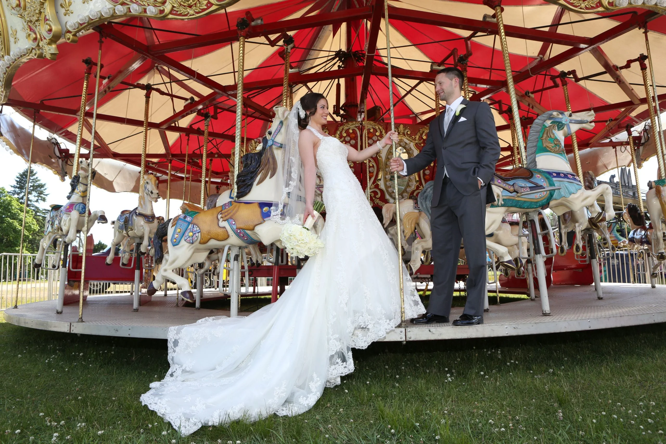 A bride and groom standing on a carousel.