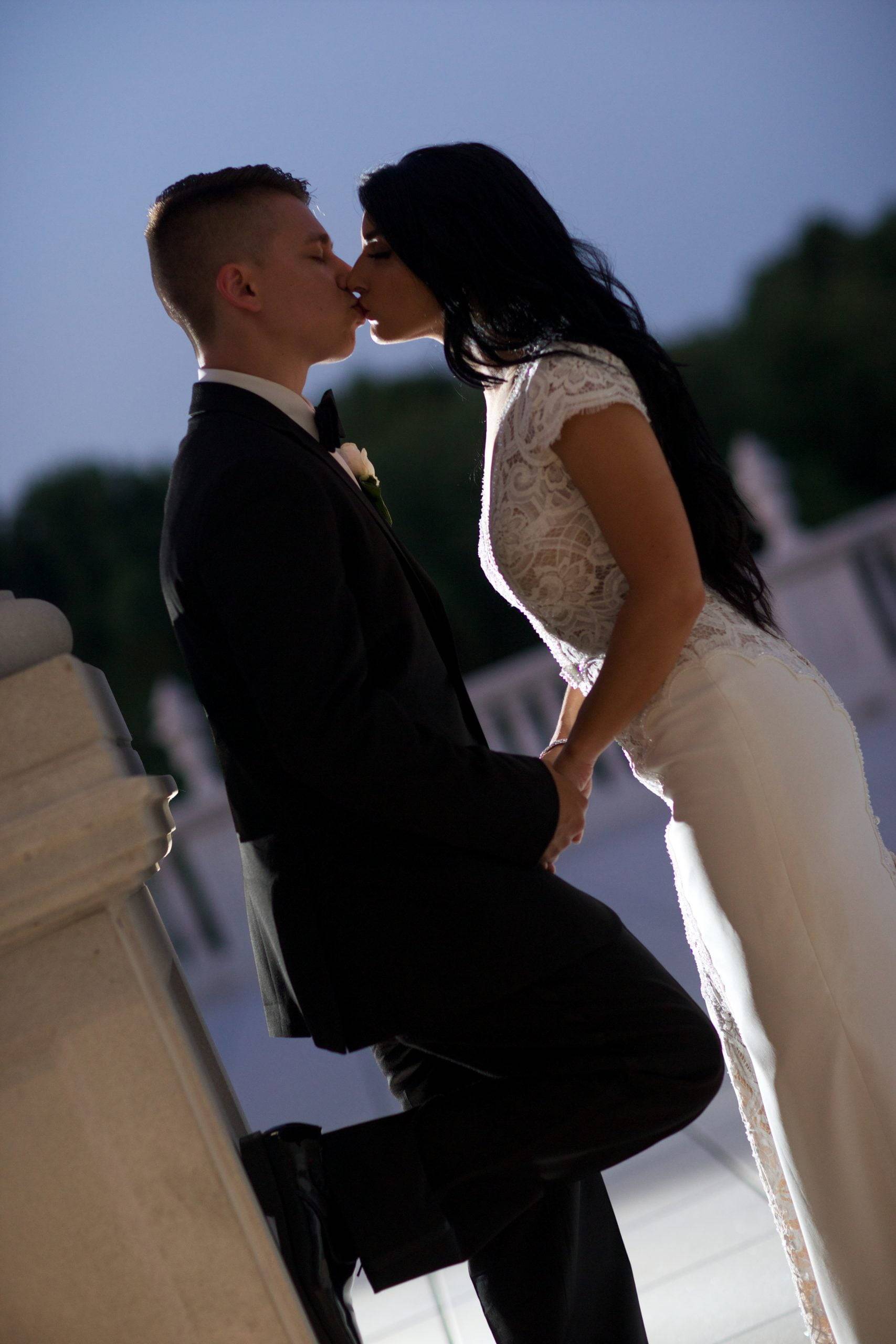 A bride and groom kissing on the steps of a building.