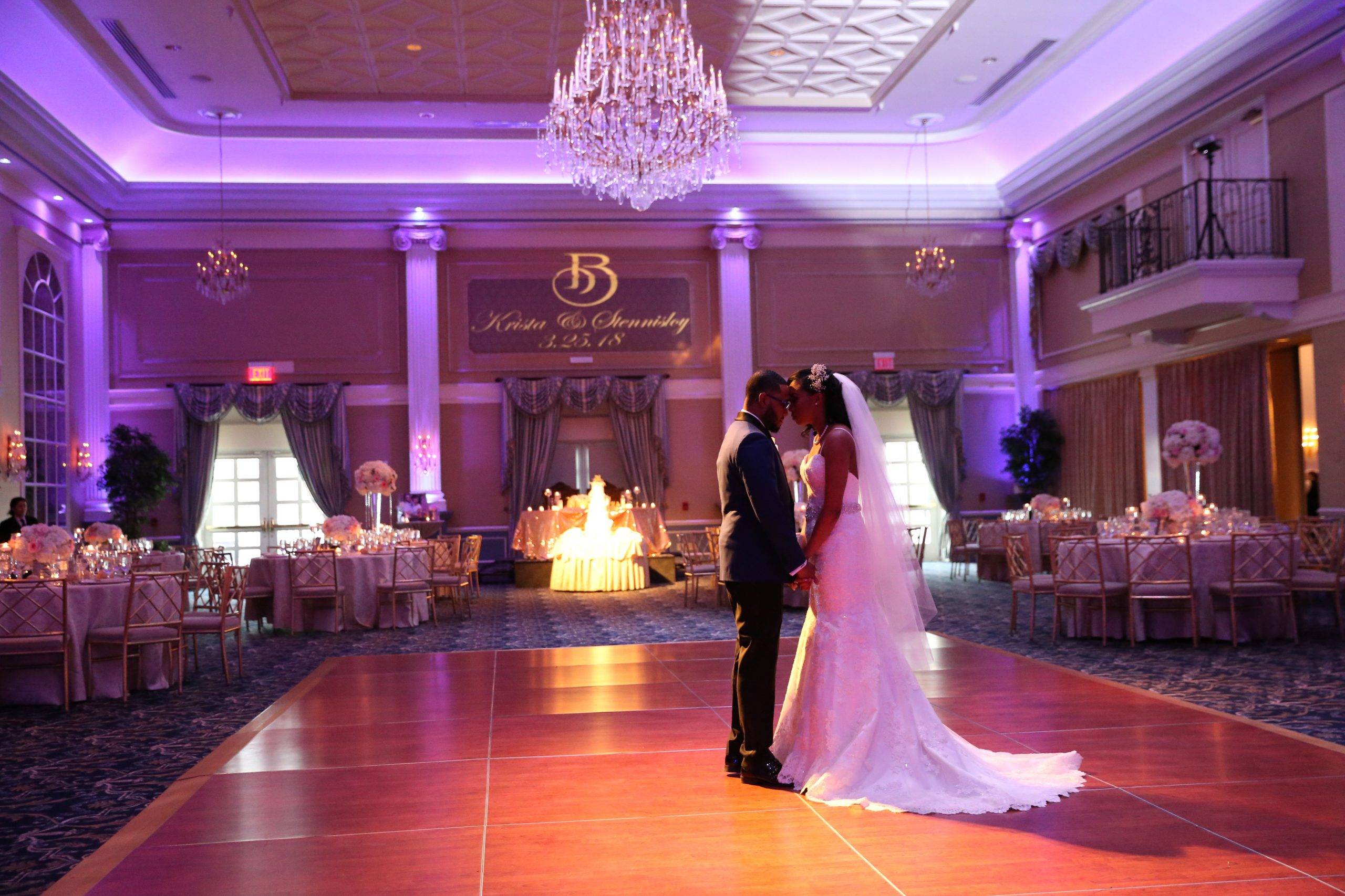 A bride and groom share their first dance in a ballroom.