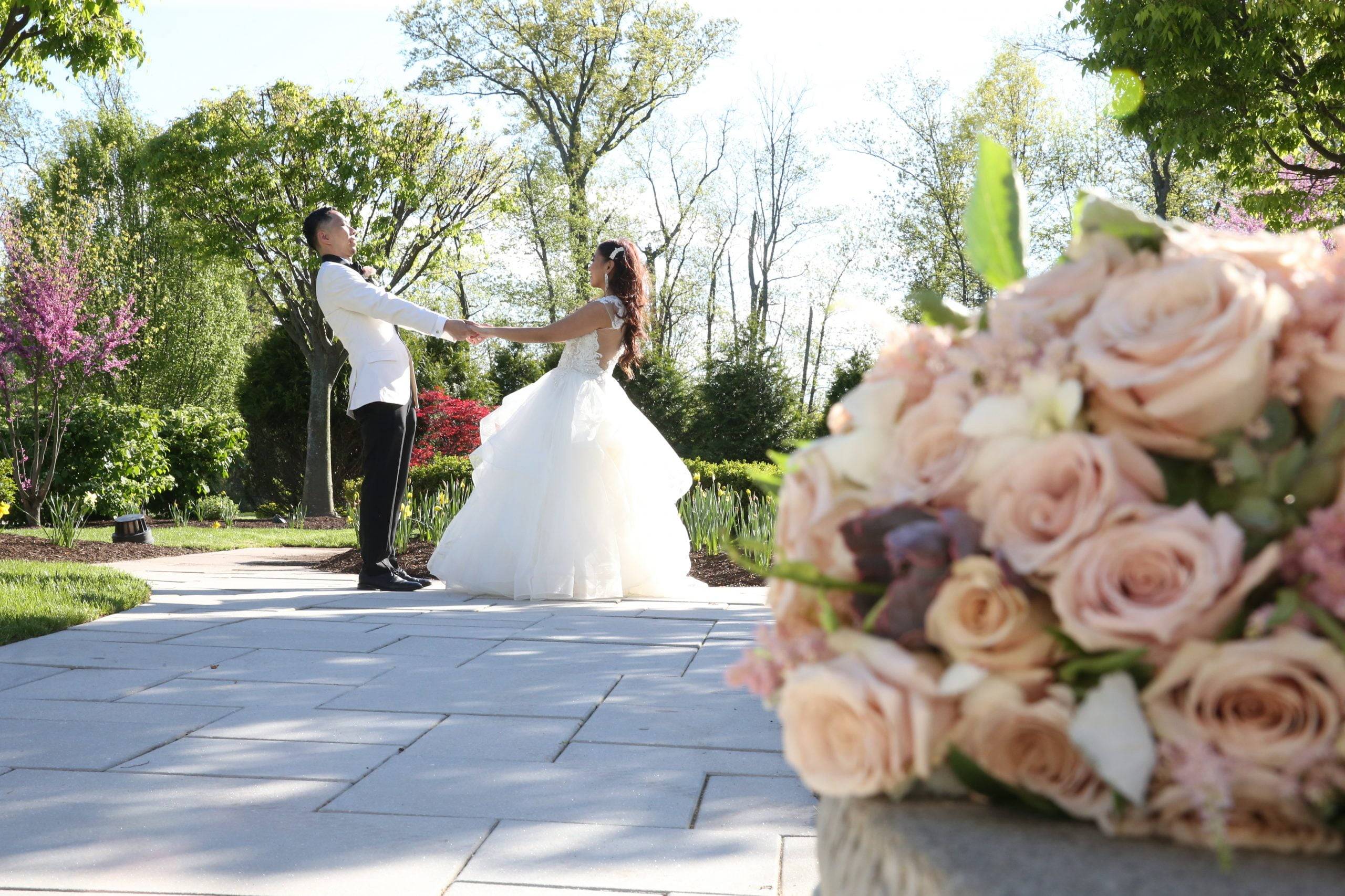 A bride and groom are walking down a path in a garden.