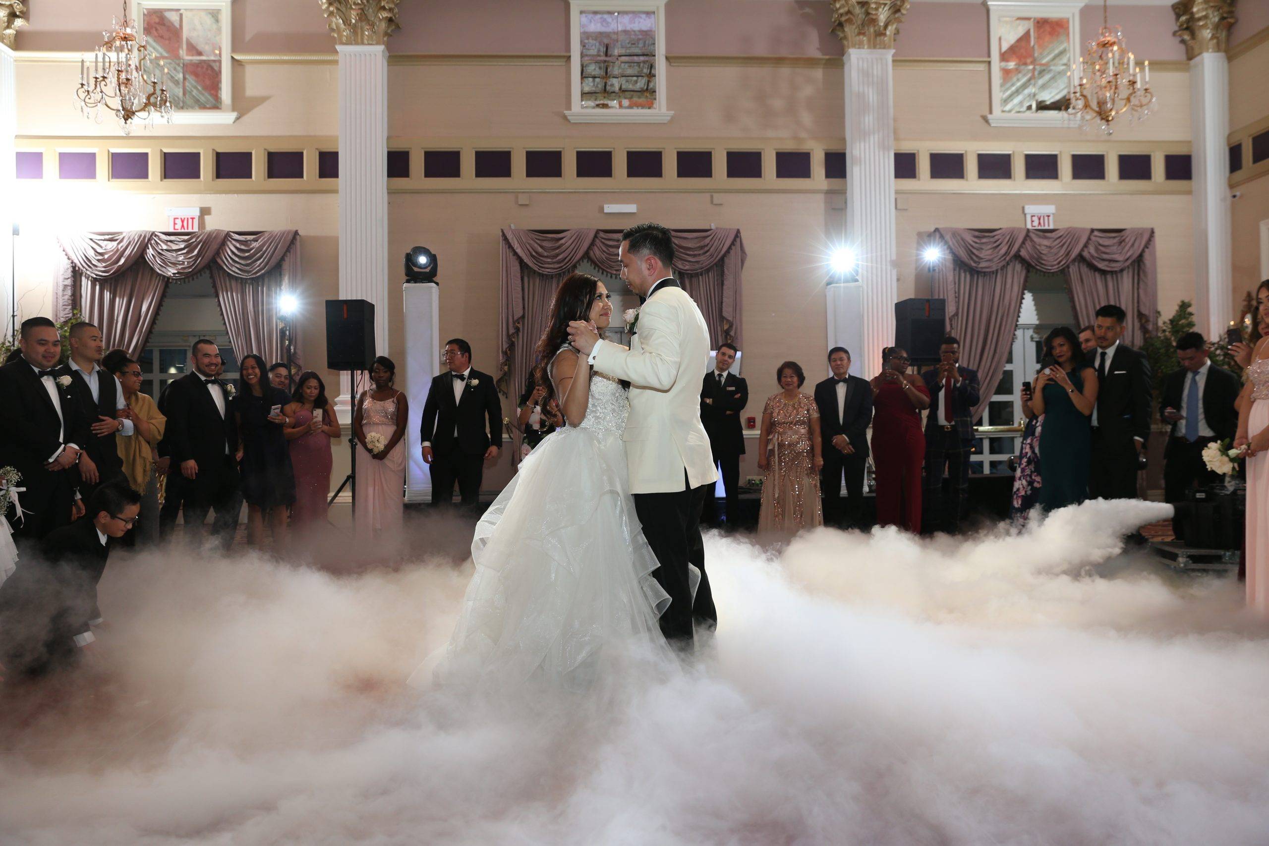 A bride and groom dance in a cloud of smoke.