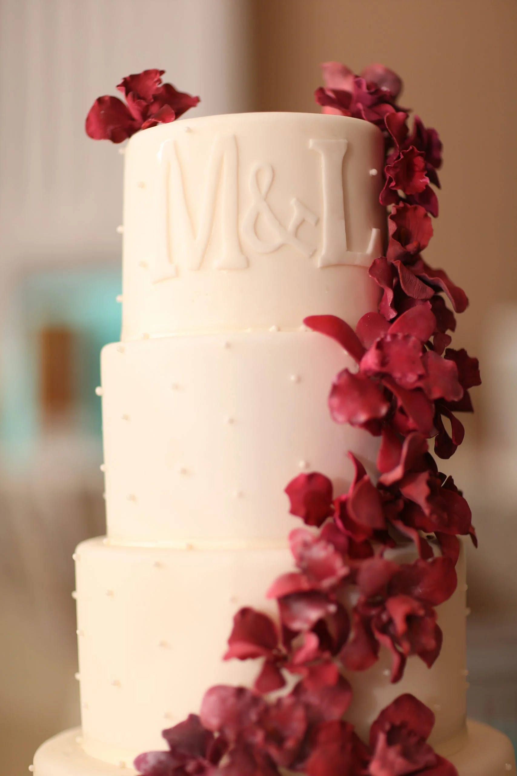 A white wedding cake with red flowers.