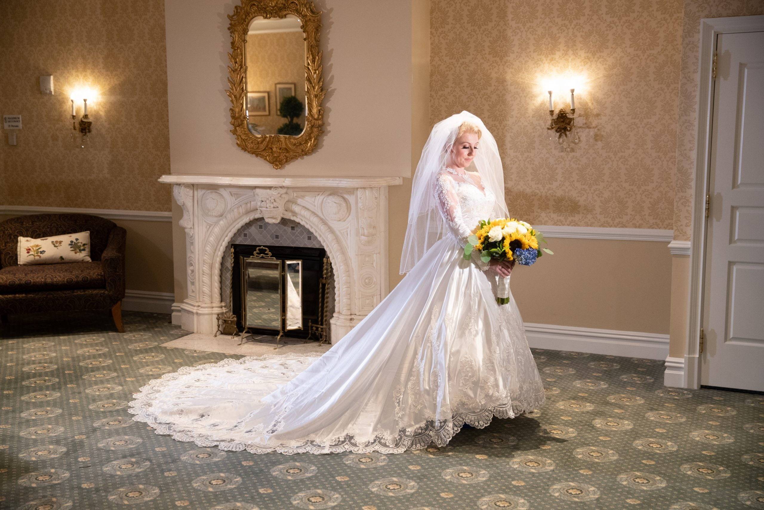 A bride in a wedding dress standing in front of a fireplace.