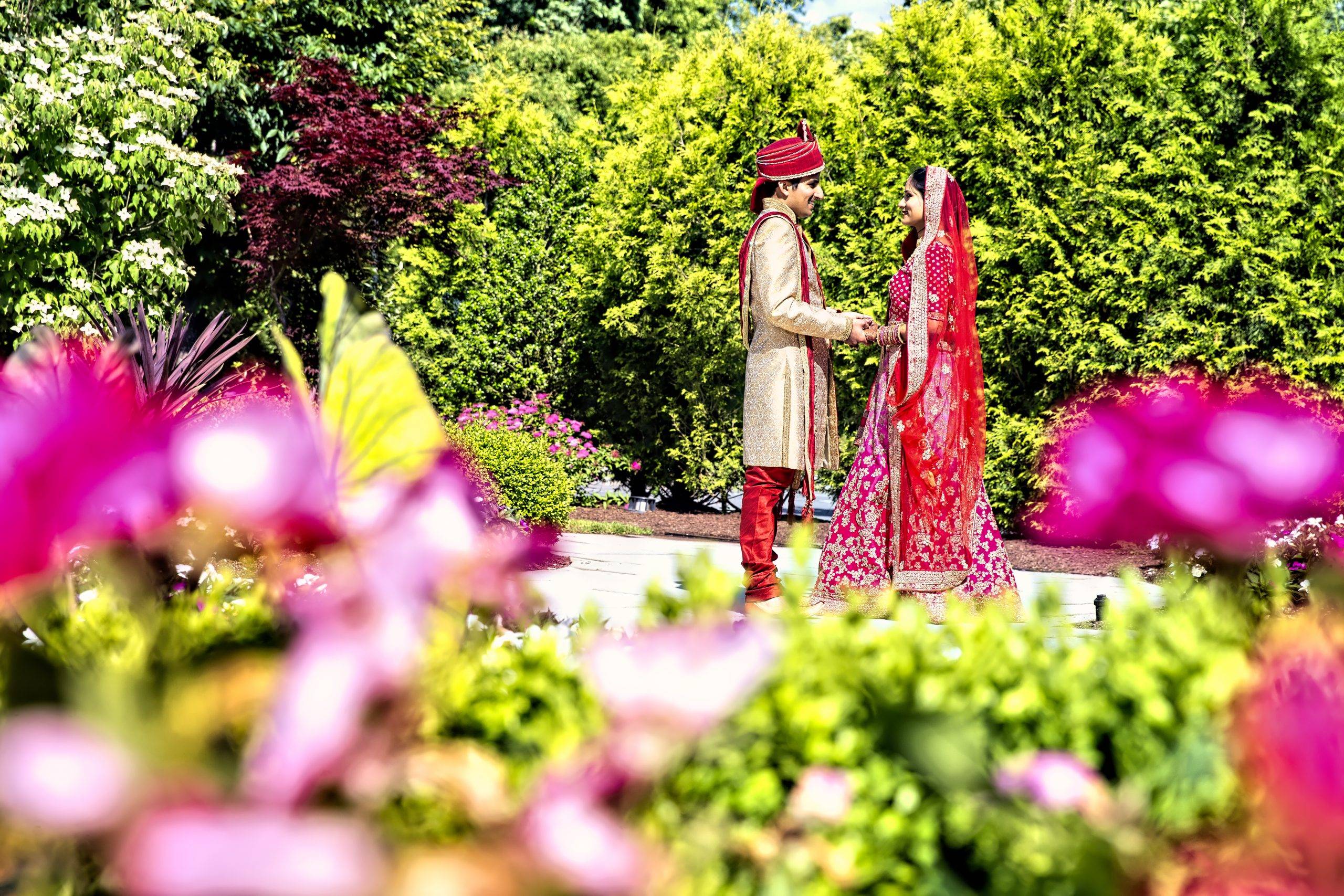A bride and groom standing in a garden with flowers.