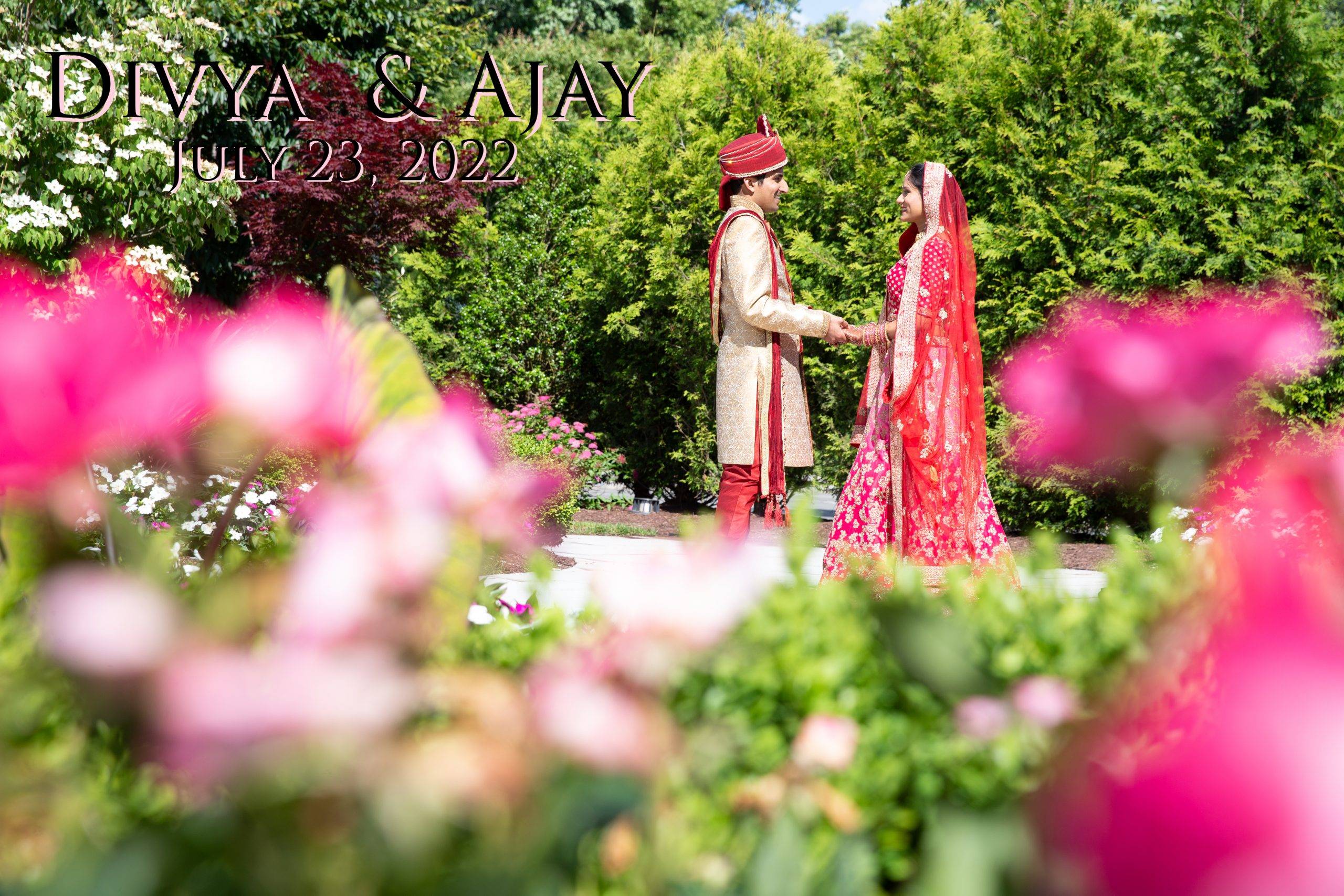 A bride and groom standing in a garden with pink flowers.