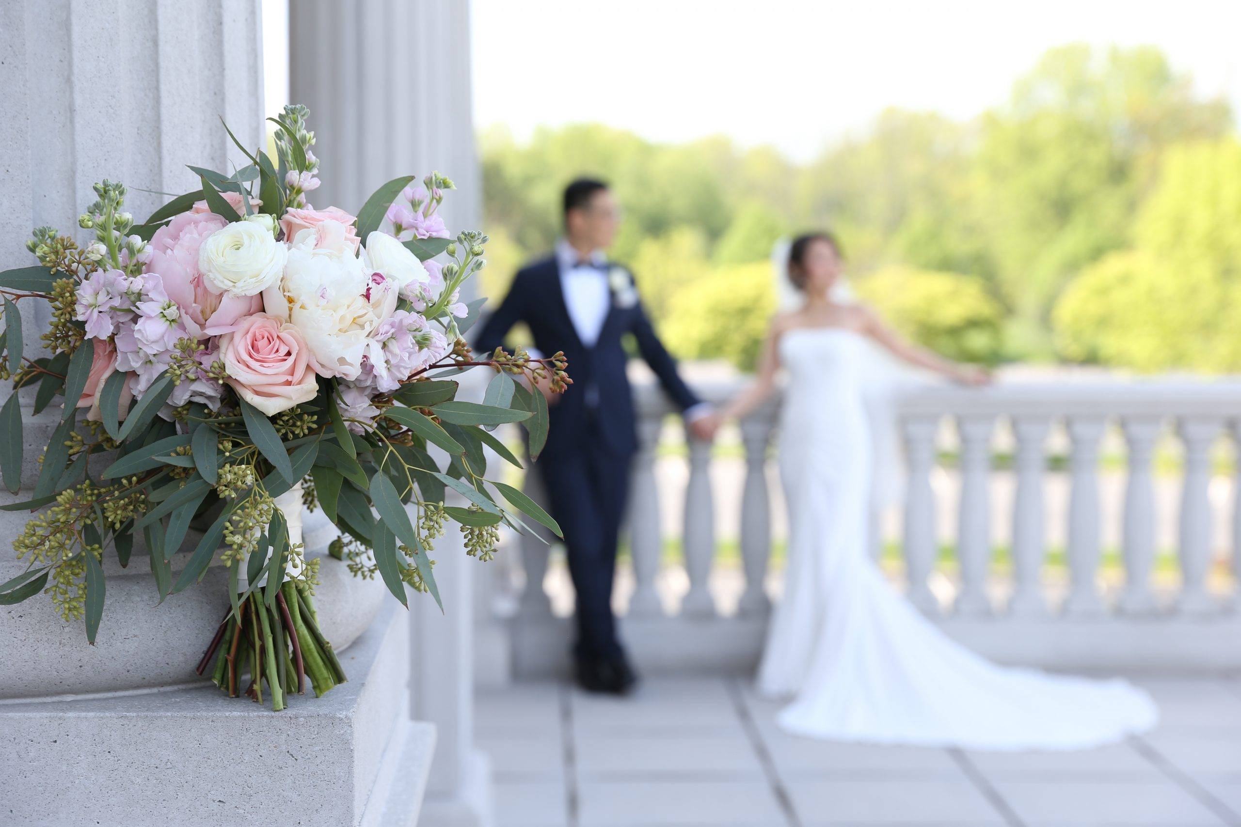 A bride and groom standing next to a bouquet.