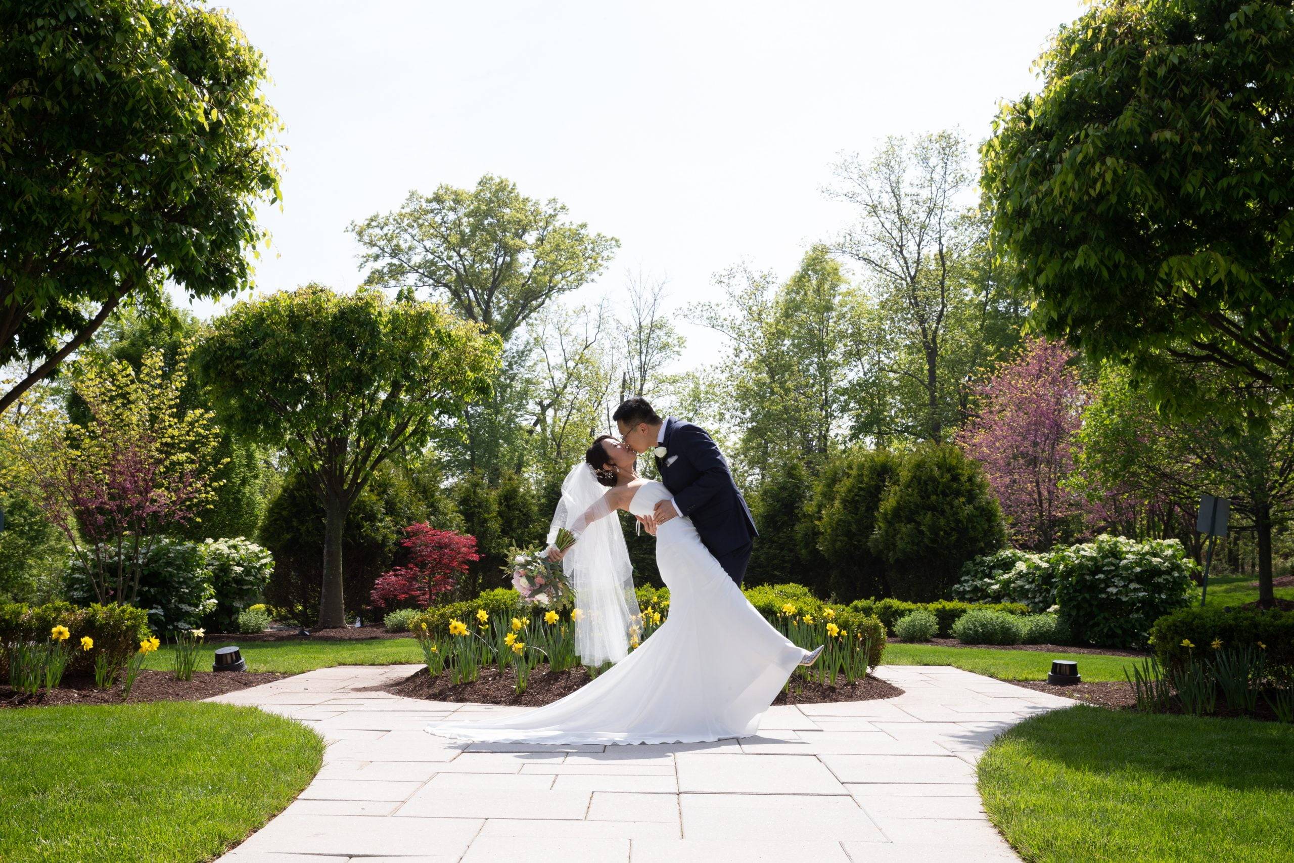 A bride and groom kissing in a garden.