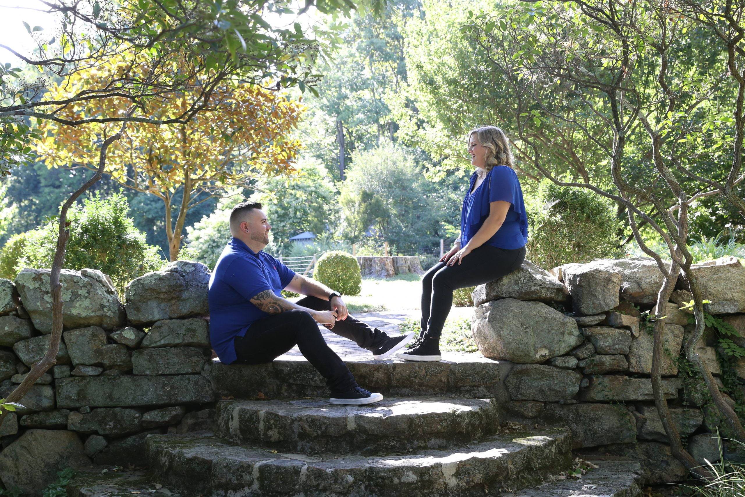 A man and woman sitting on stone steps in a garden.