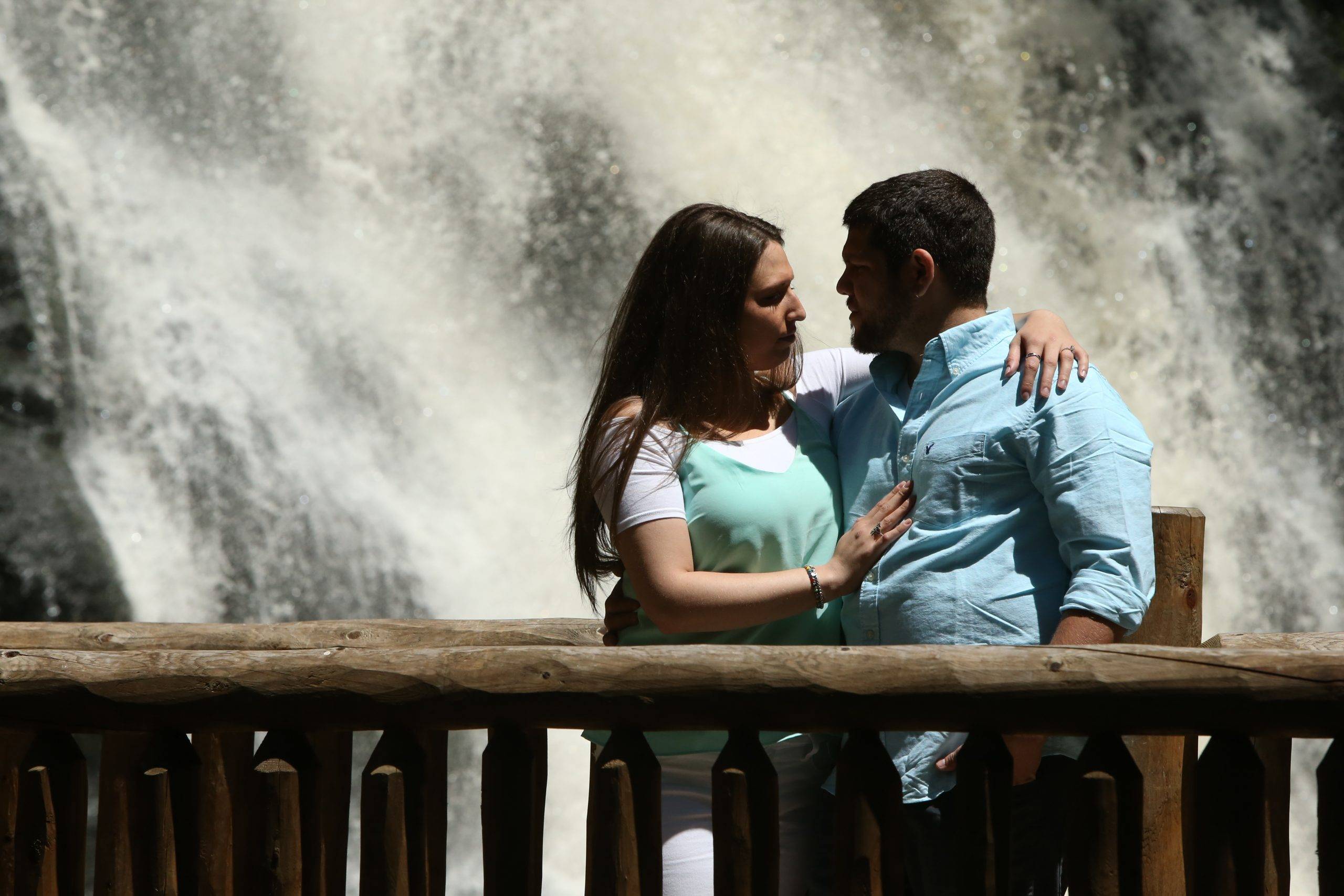 A couple standing in front of a waterfall.