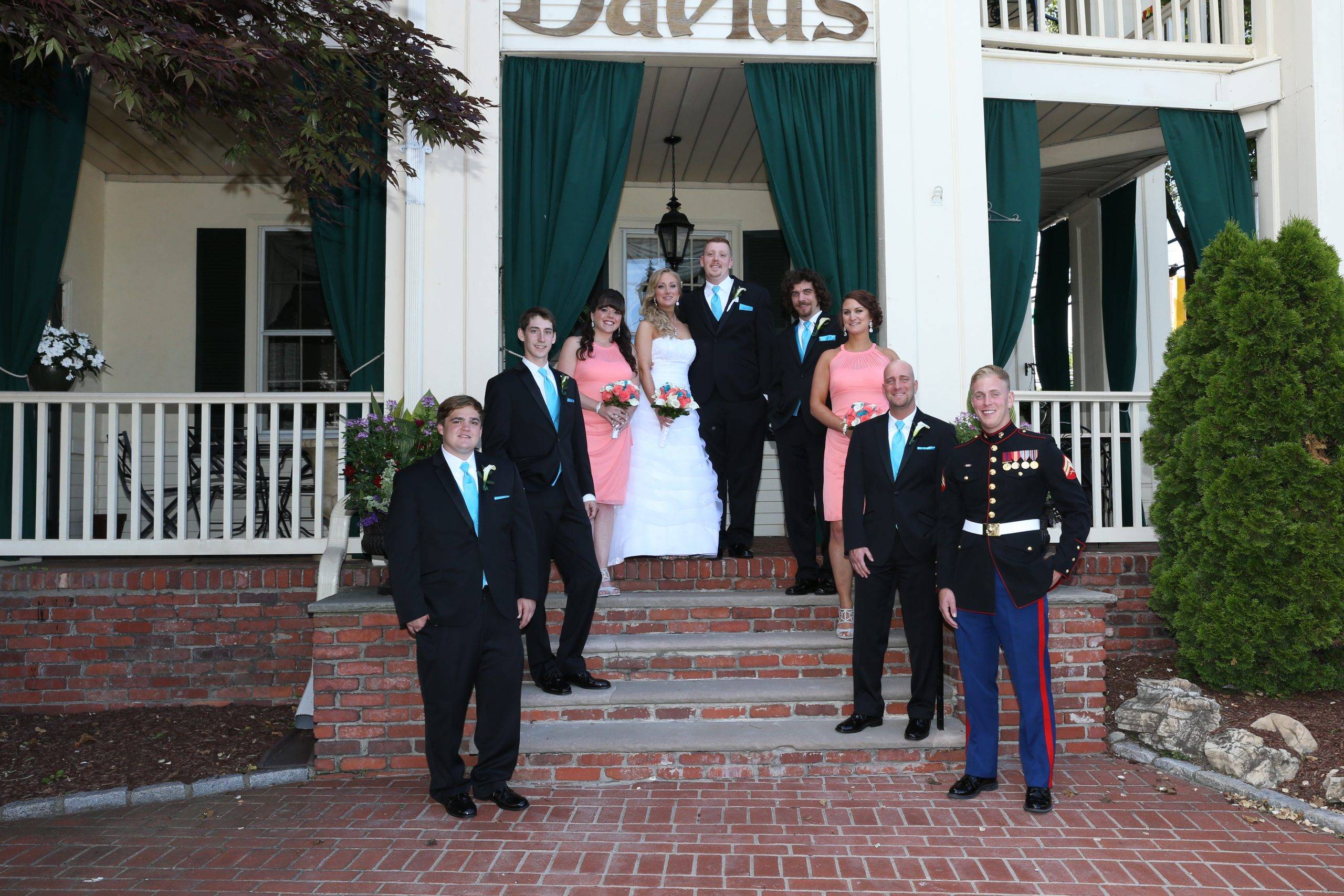 A wedding party posing in front of a house.