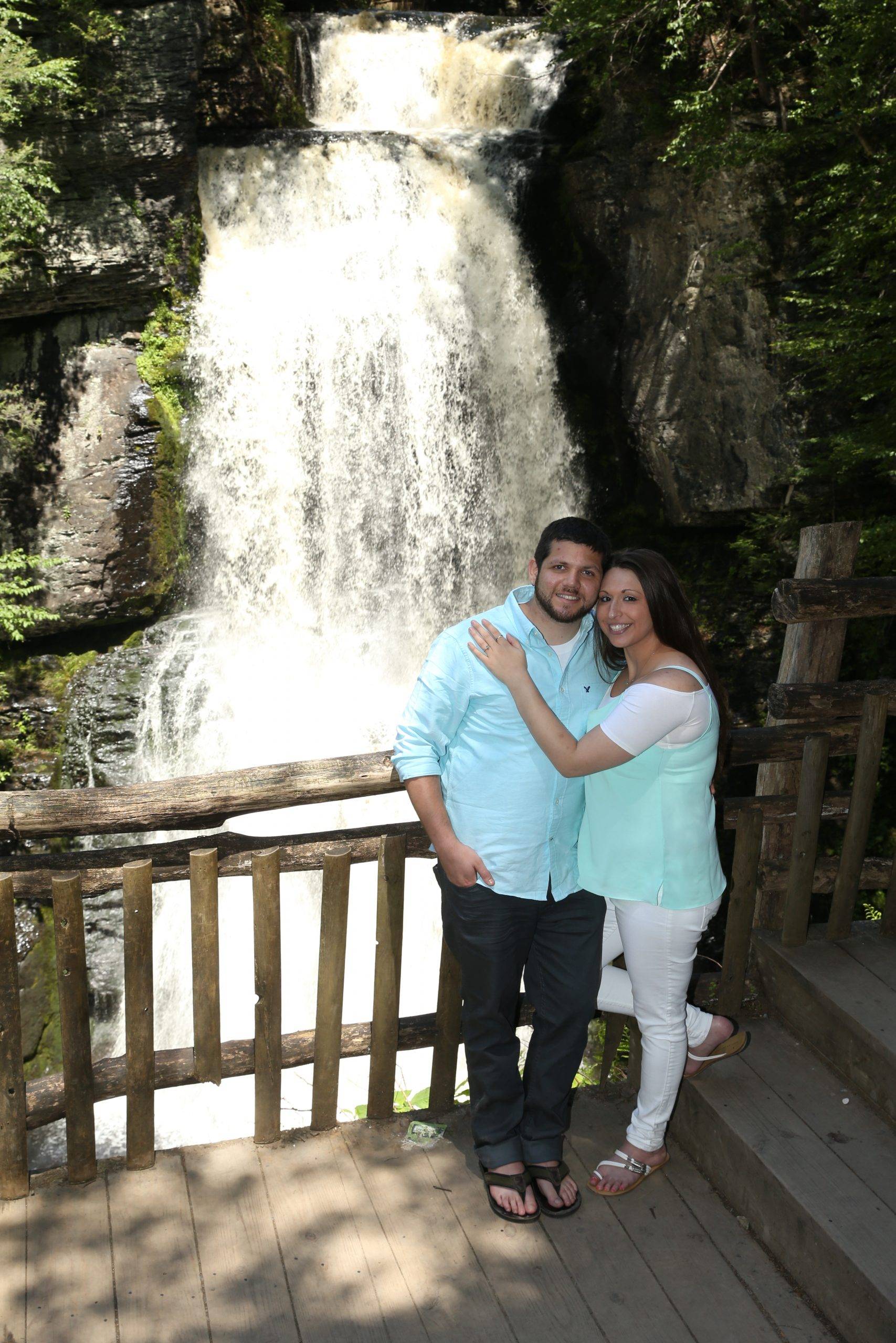 A man and woman standing in front of a waterfall.