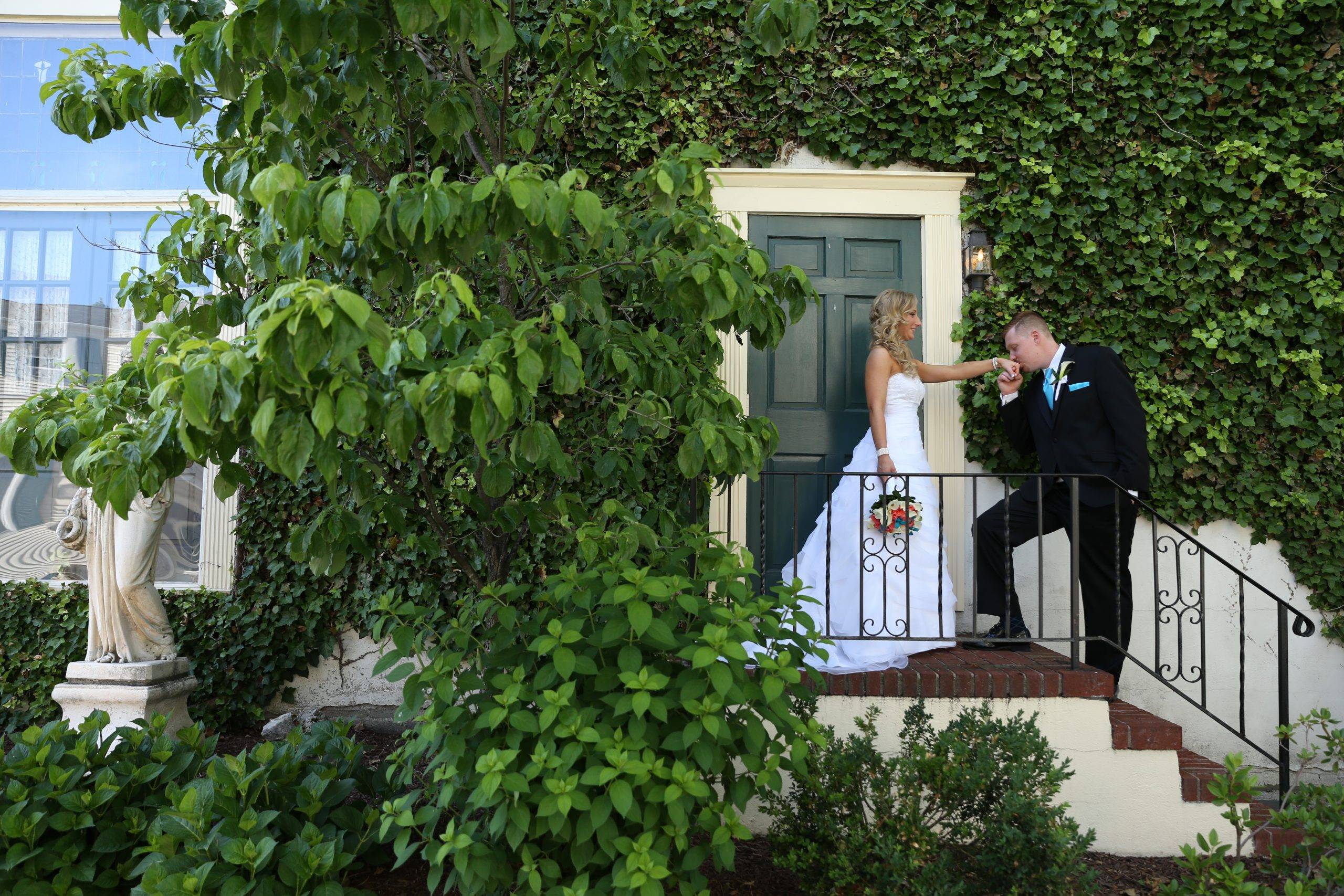 A bride and groom kissing on the steps of a house.