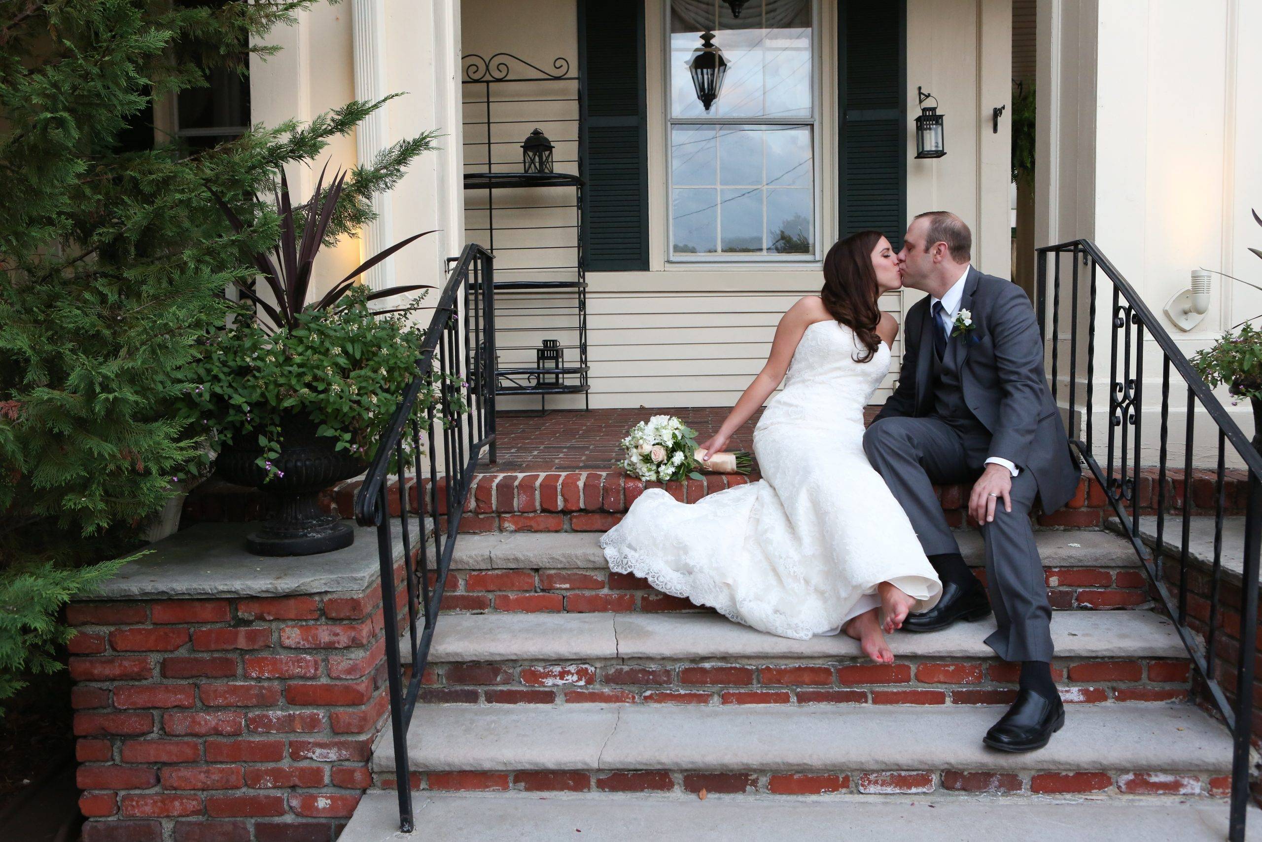 A bride and groom sitting on the steps of a house.