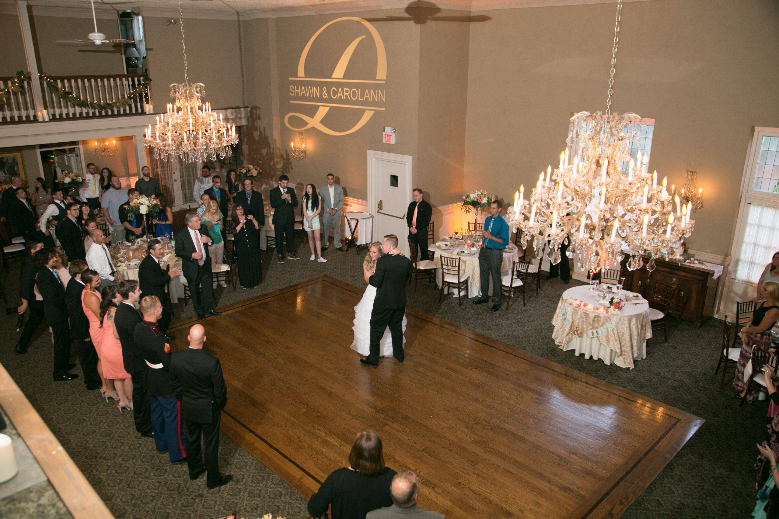 A bride and groom dance in a large room with chandeliers.