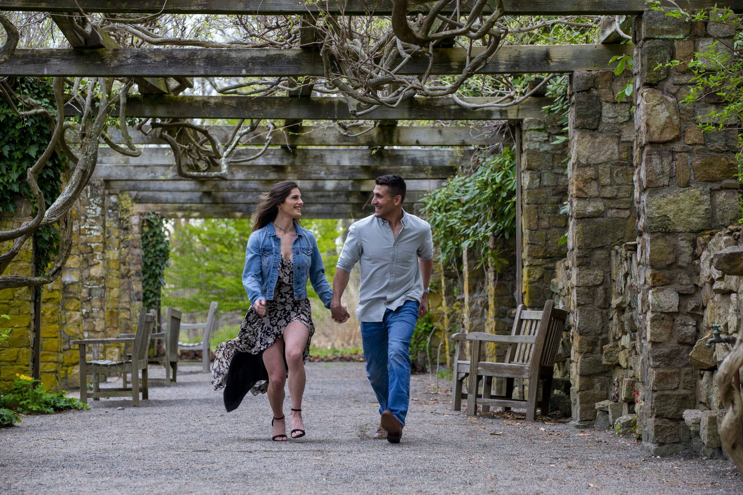 An engaged couple walking through an arboretum.