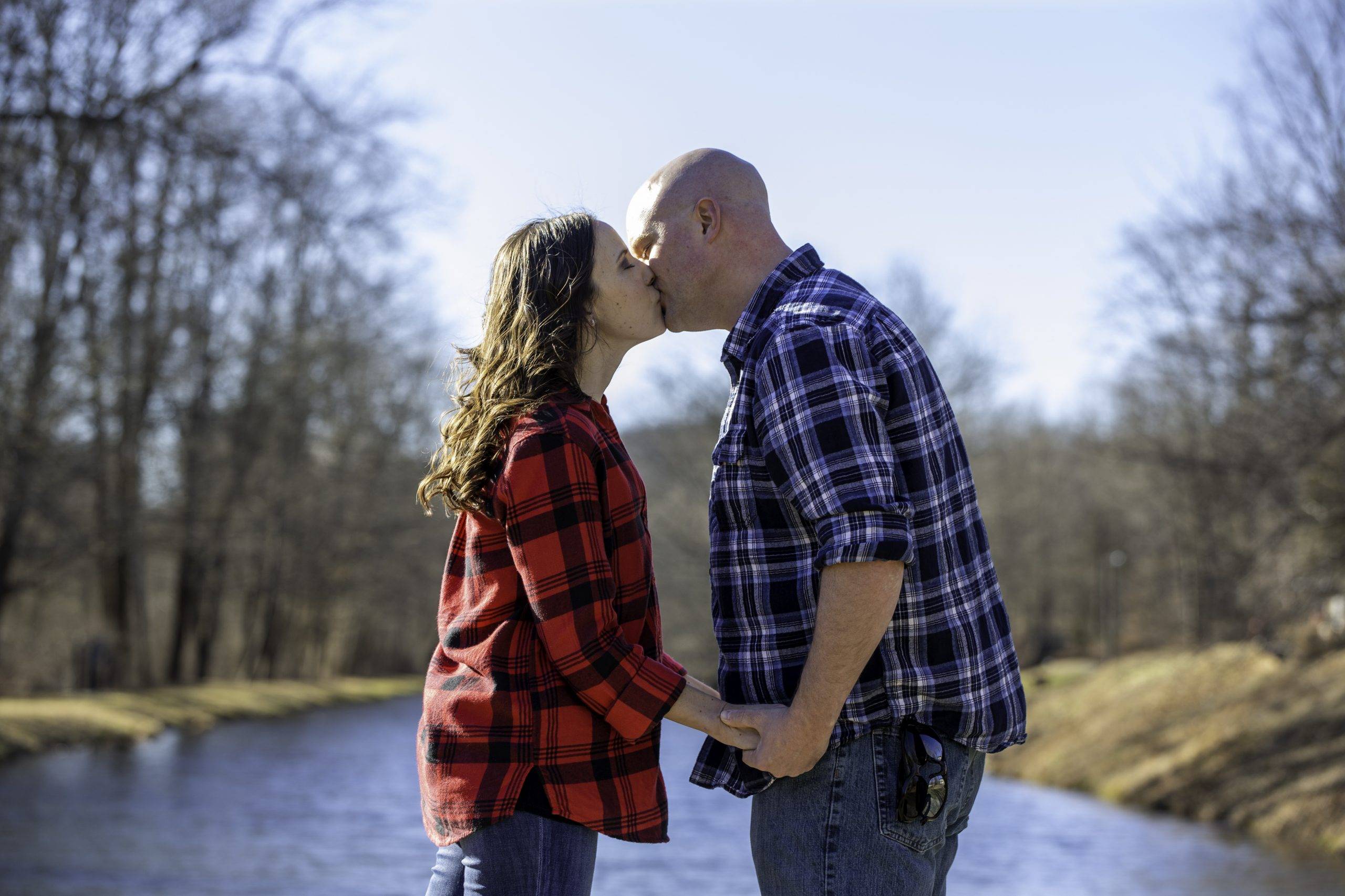 A couple kissing in front of a river.