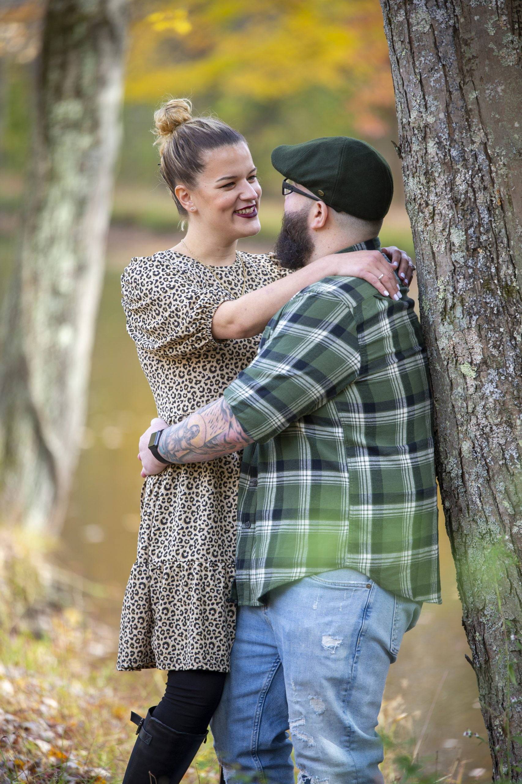 A couple embraces in front of a tree during their engagement session.