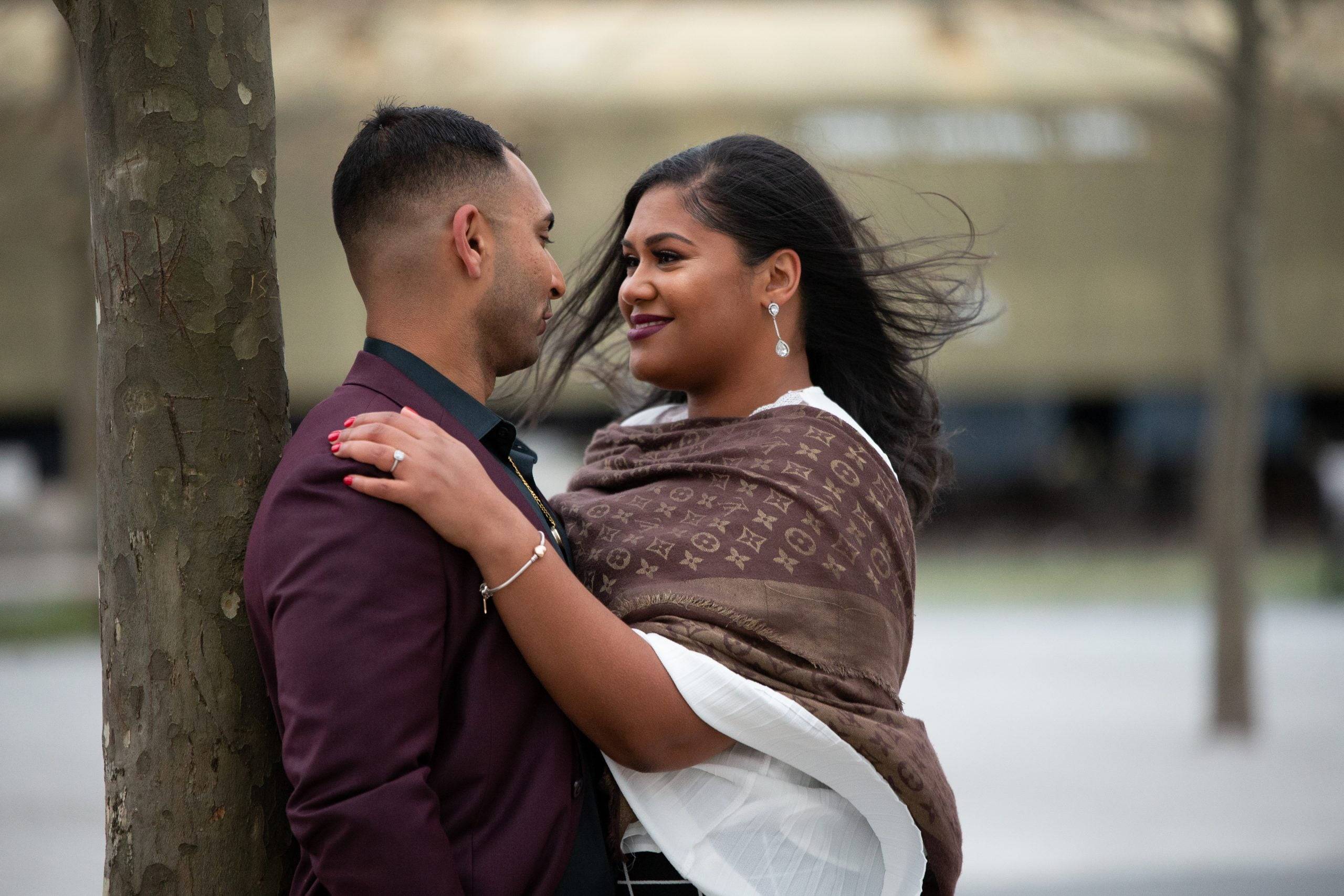 An indian couple hugging in front of a tree.