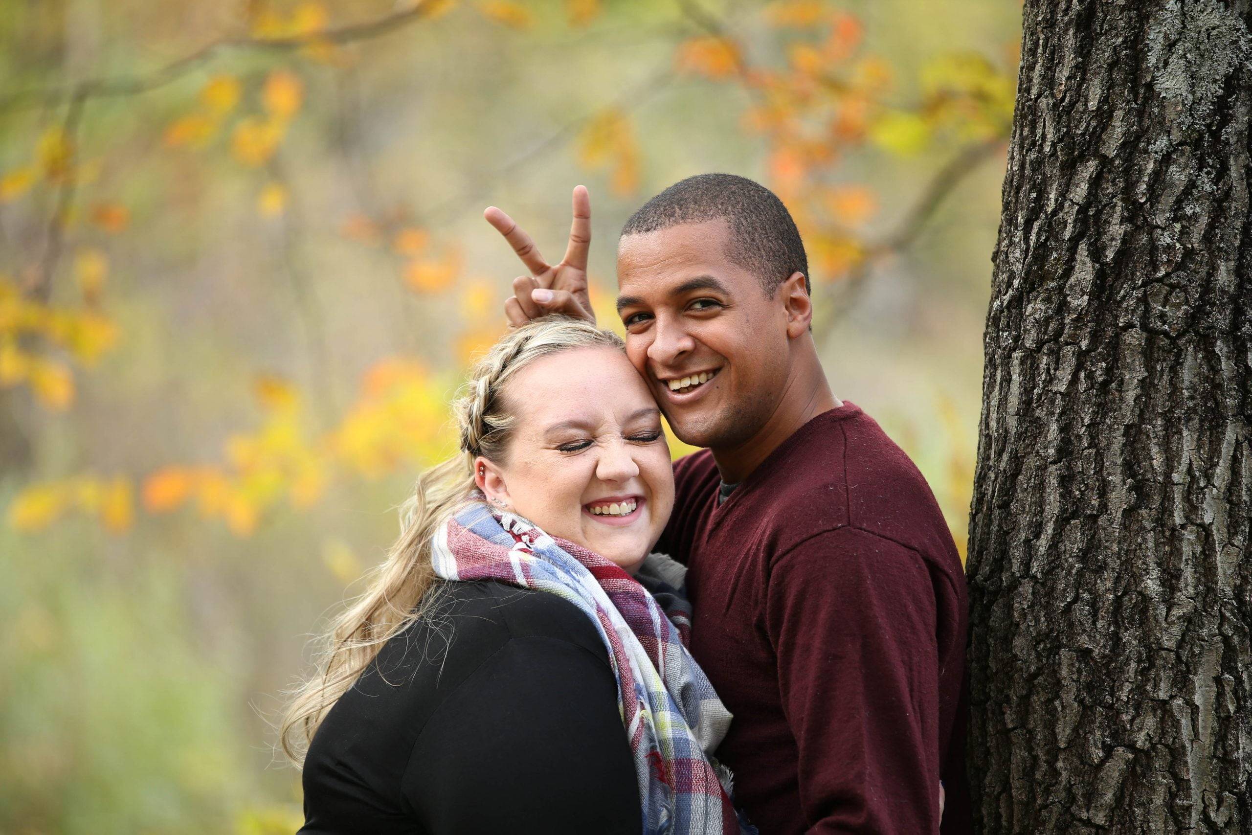 A man and woman posing for a photo in the fall.