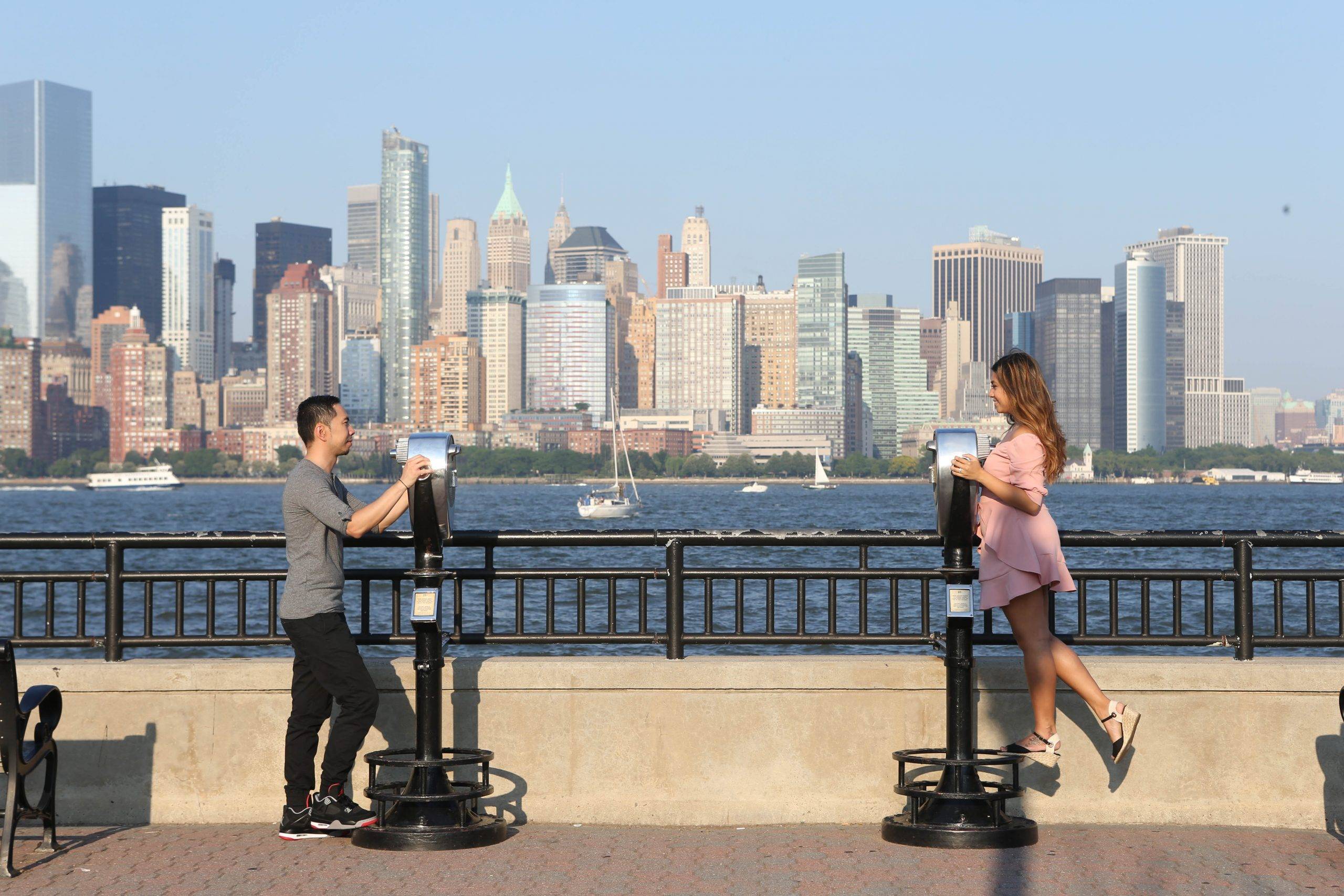 Two people standing on a bench in front of a city skyline.