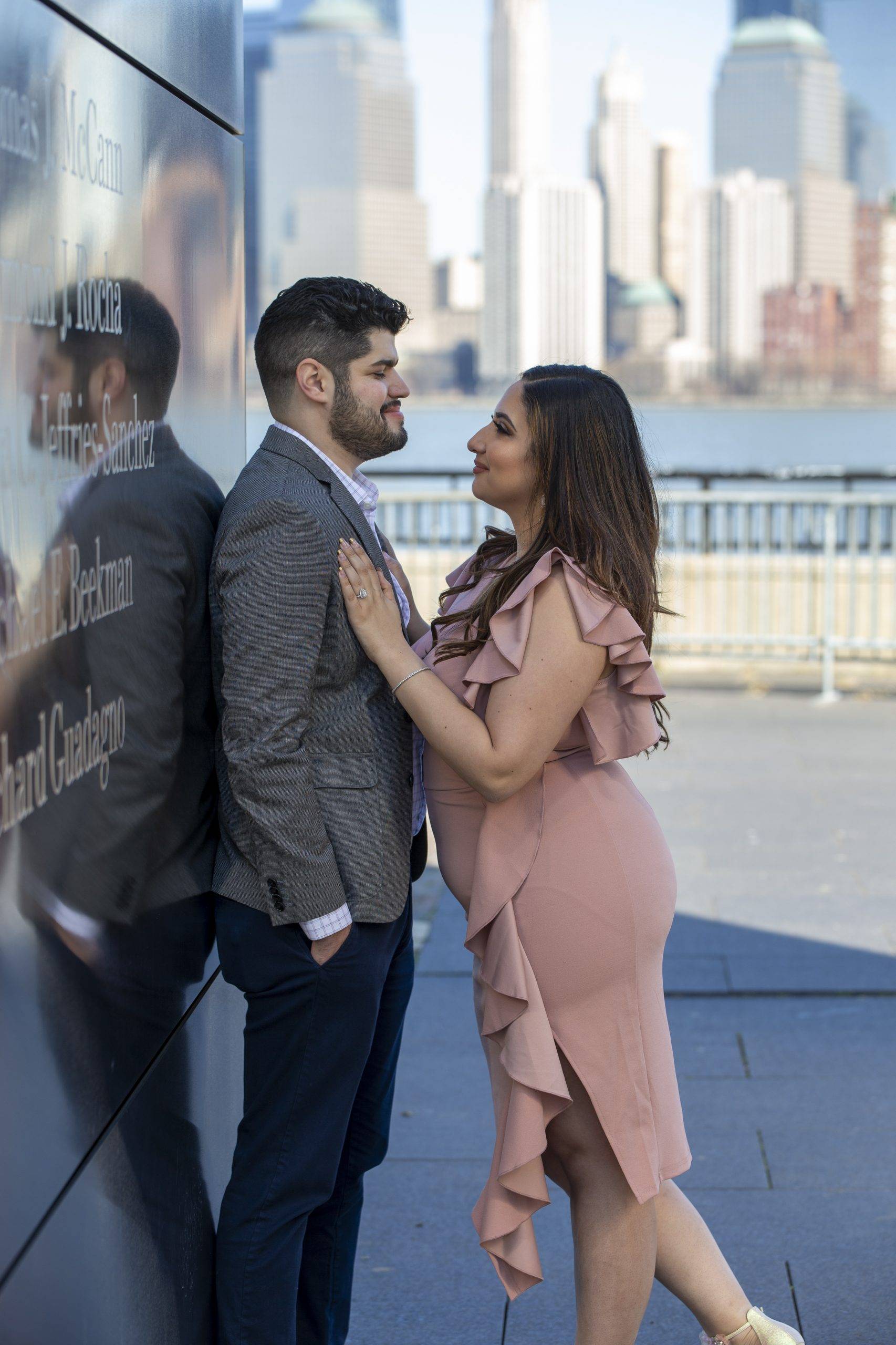 A couple is posing in front of a memorial in nyc.