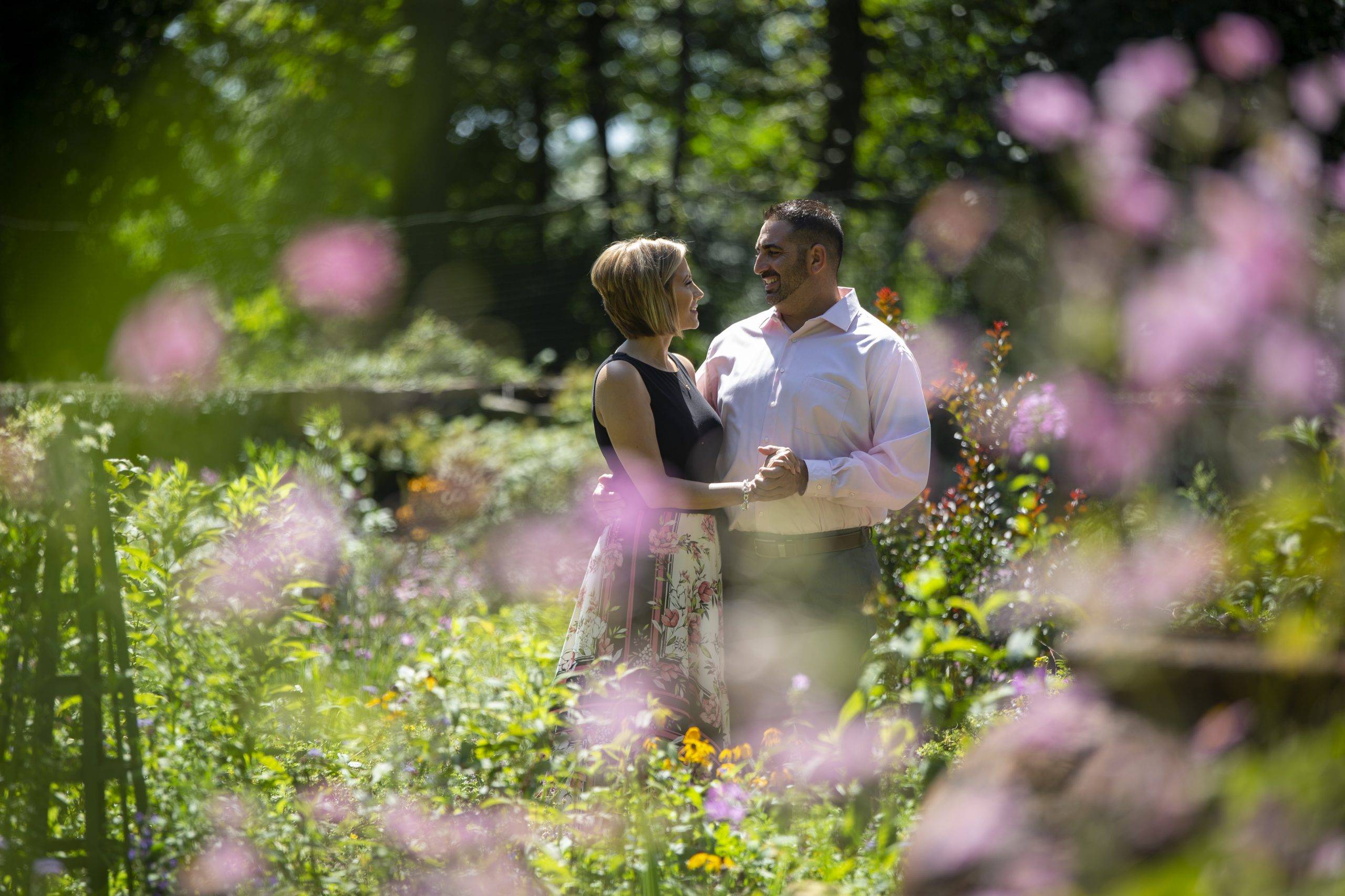 An engaged couple standing in a field of flowers.