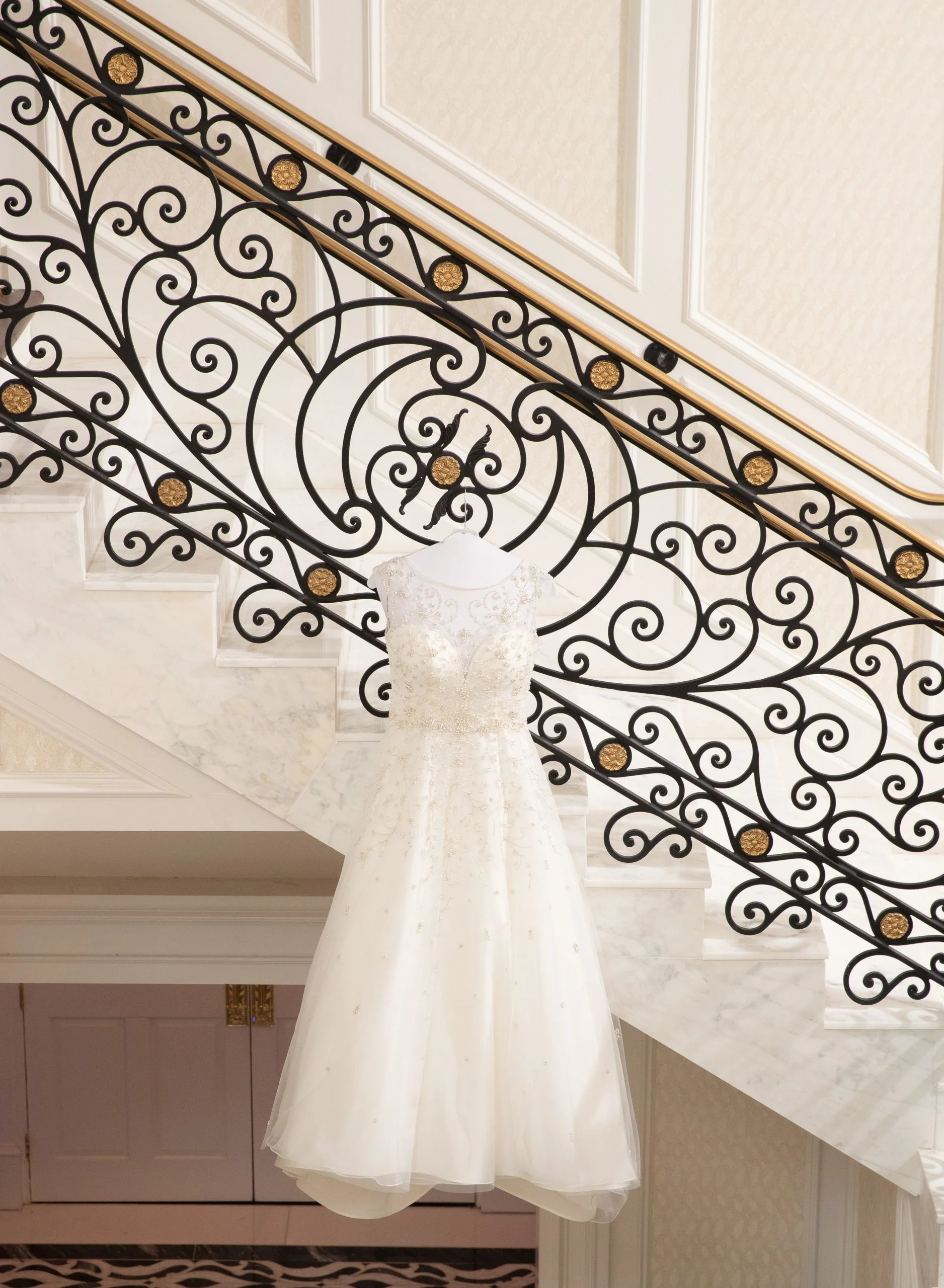 A wedding dress hangs on the stairs of a hotel.