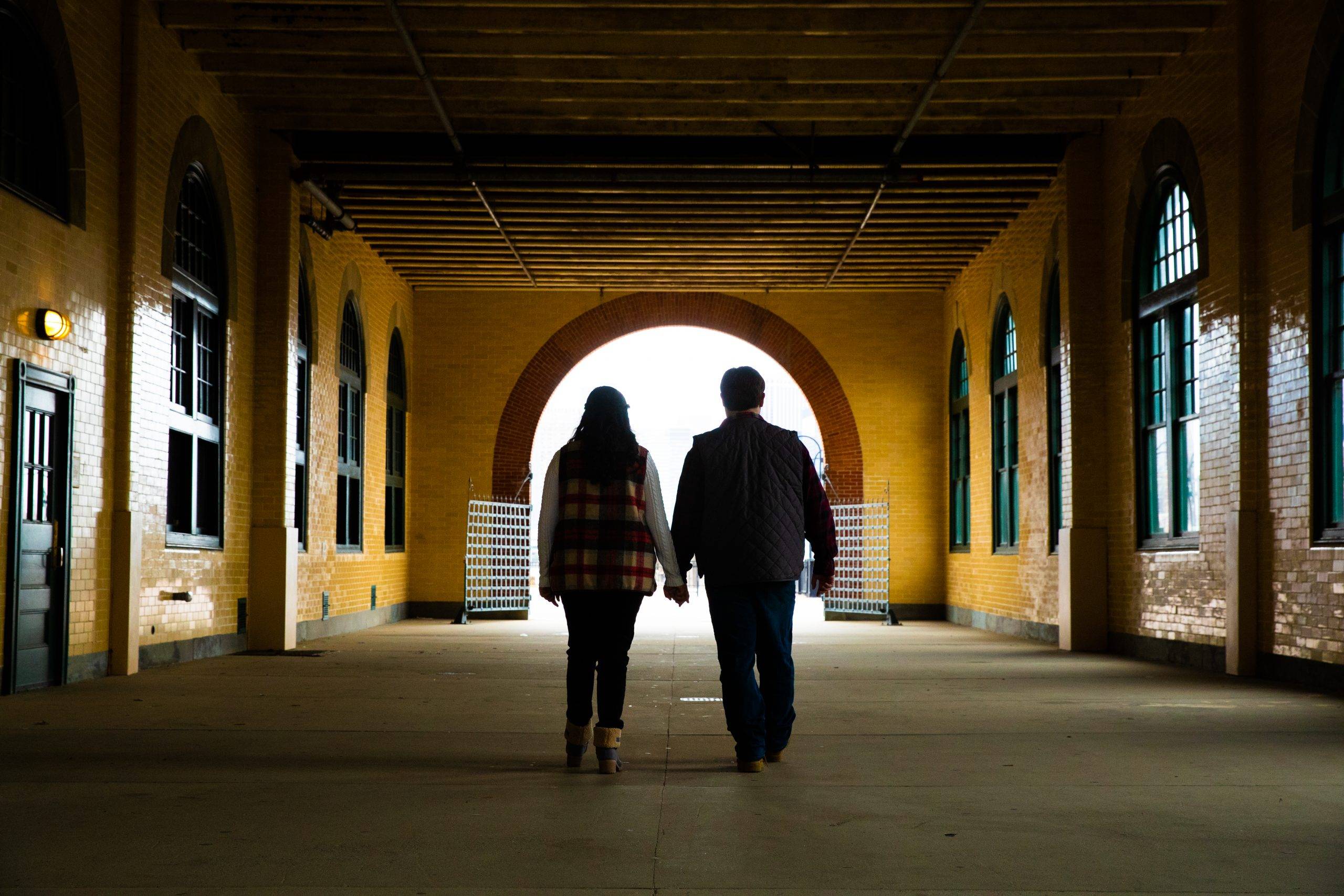 A couple walking down a hallway in an old building.