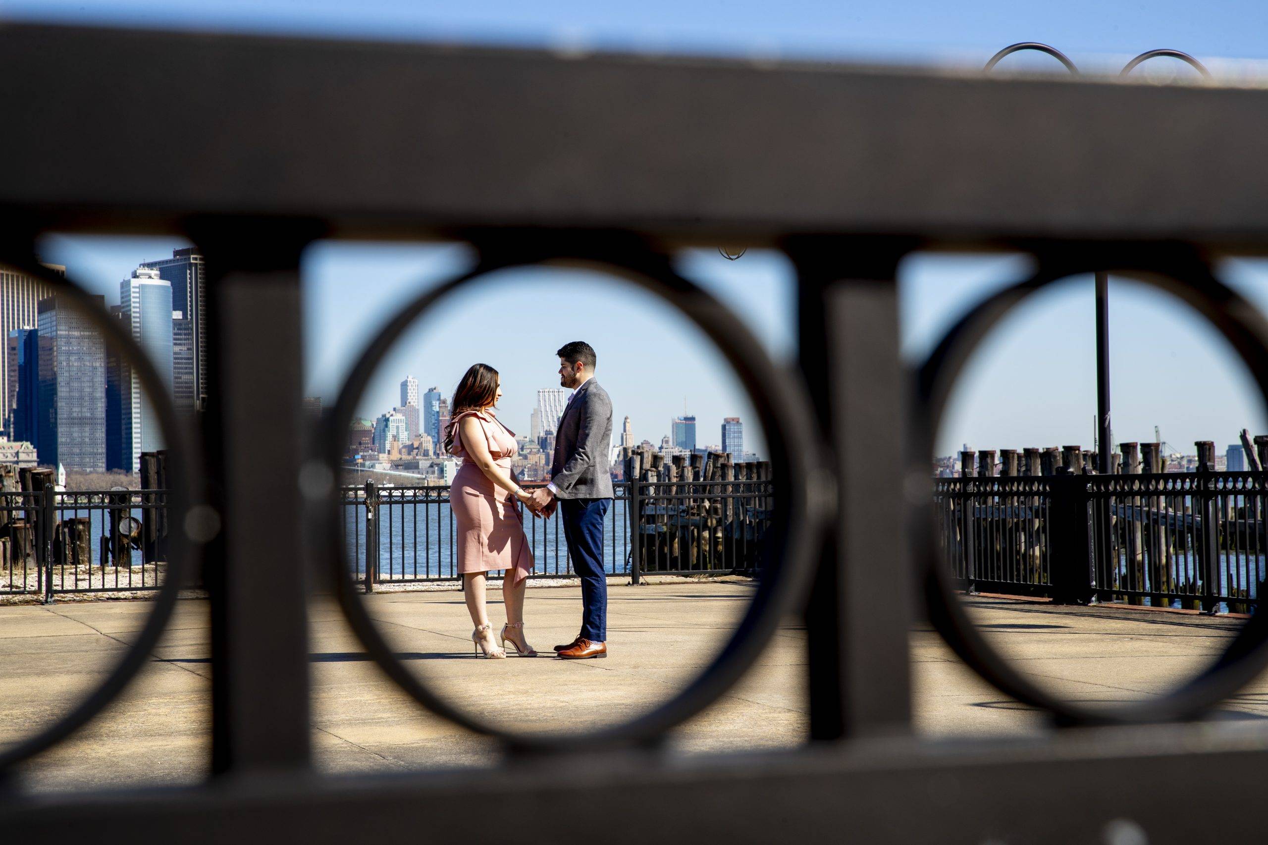 A couple standing on a bridge with a view of the city.