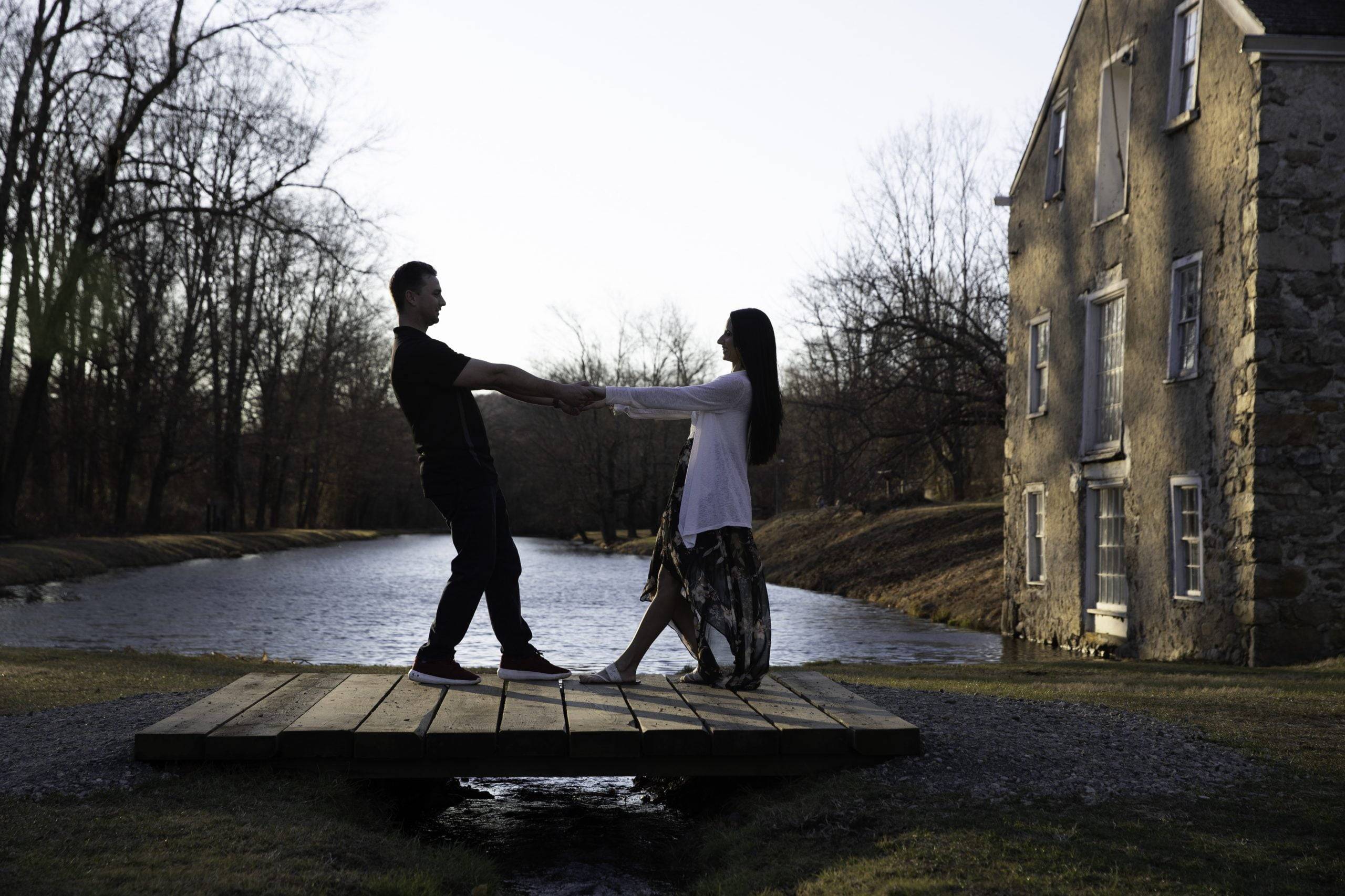 A couple standing on a bridge in front of a house.