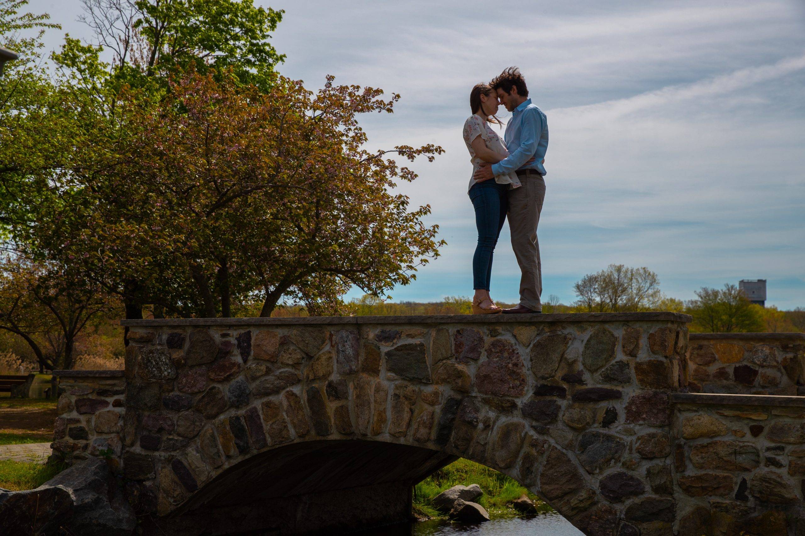 A couple standing on a stone bridge in a park.