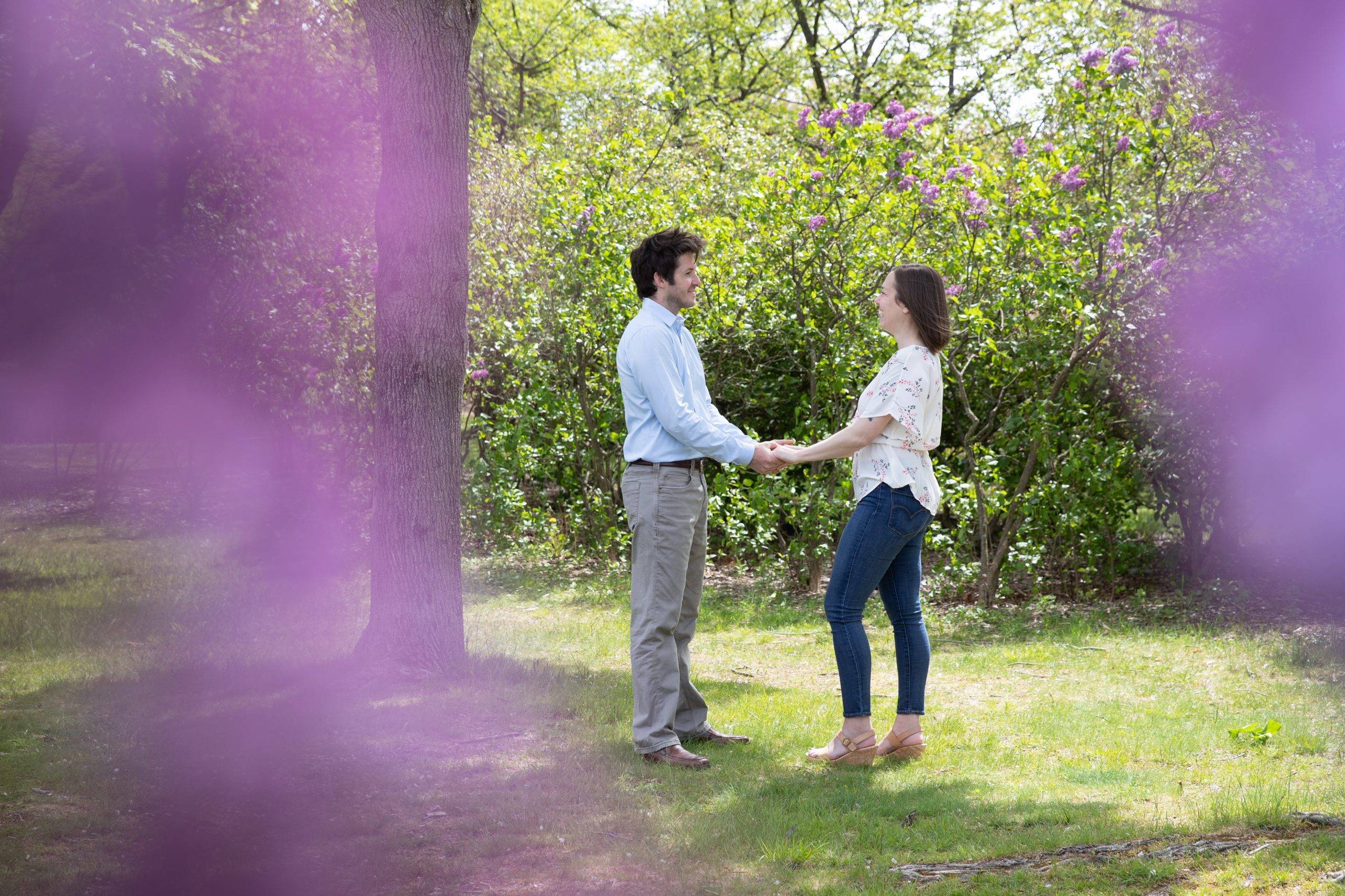 A couple holding hands in a field with purple flowers.