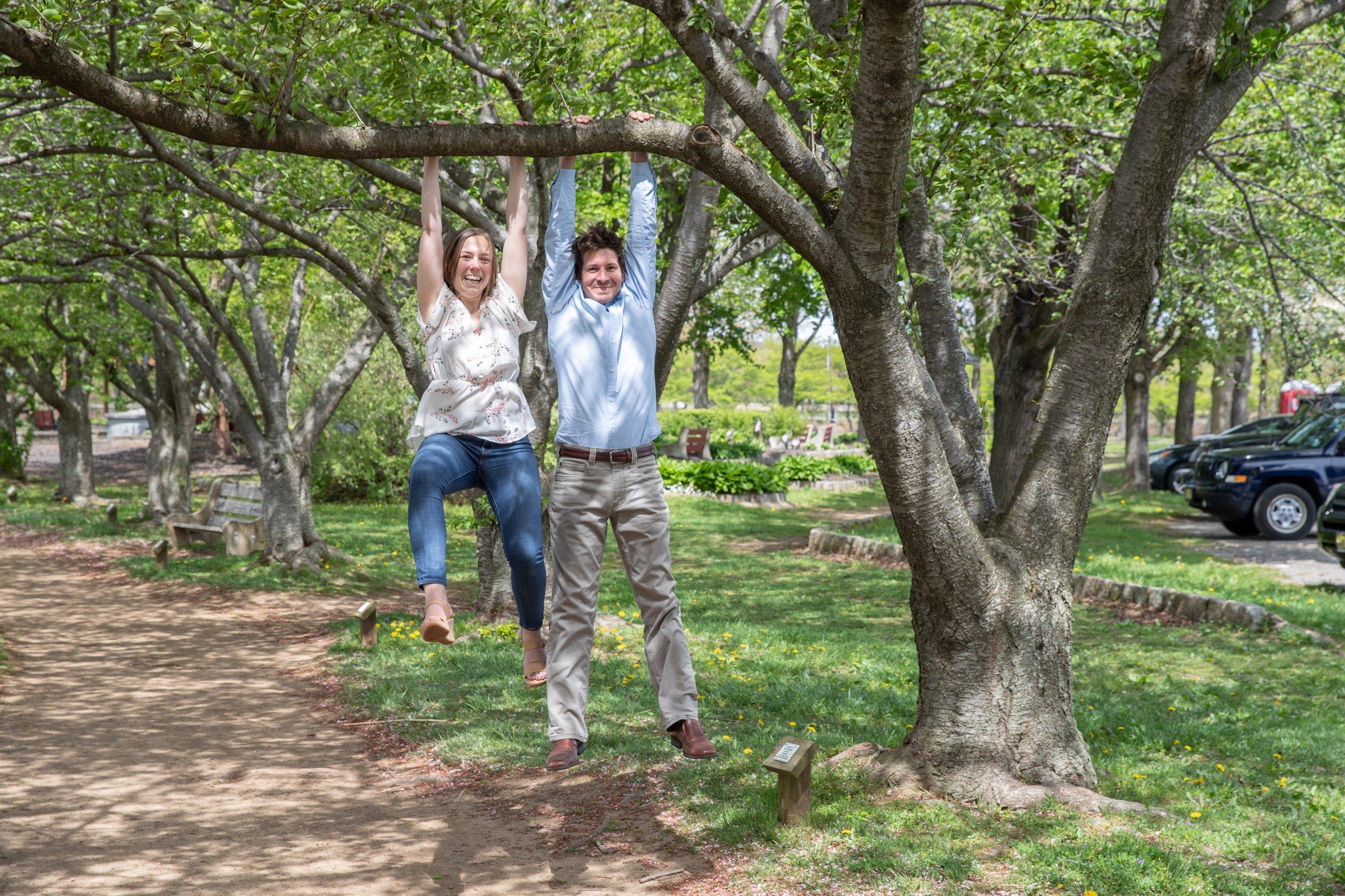 A man and woman hanging from a tree.