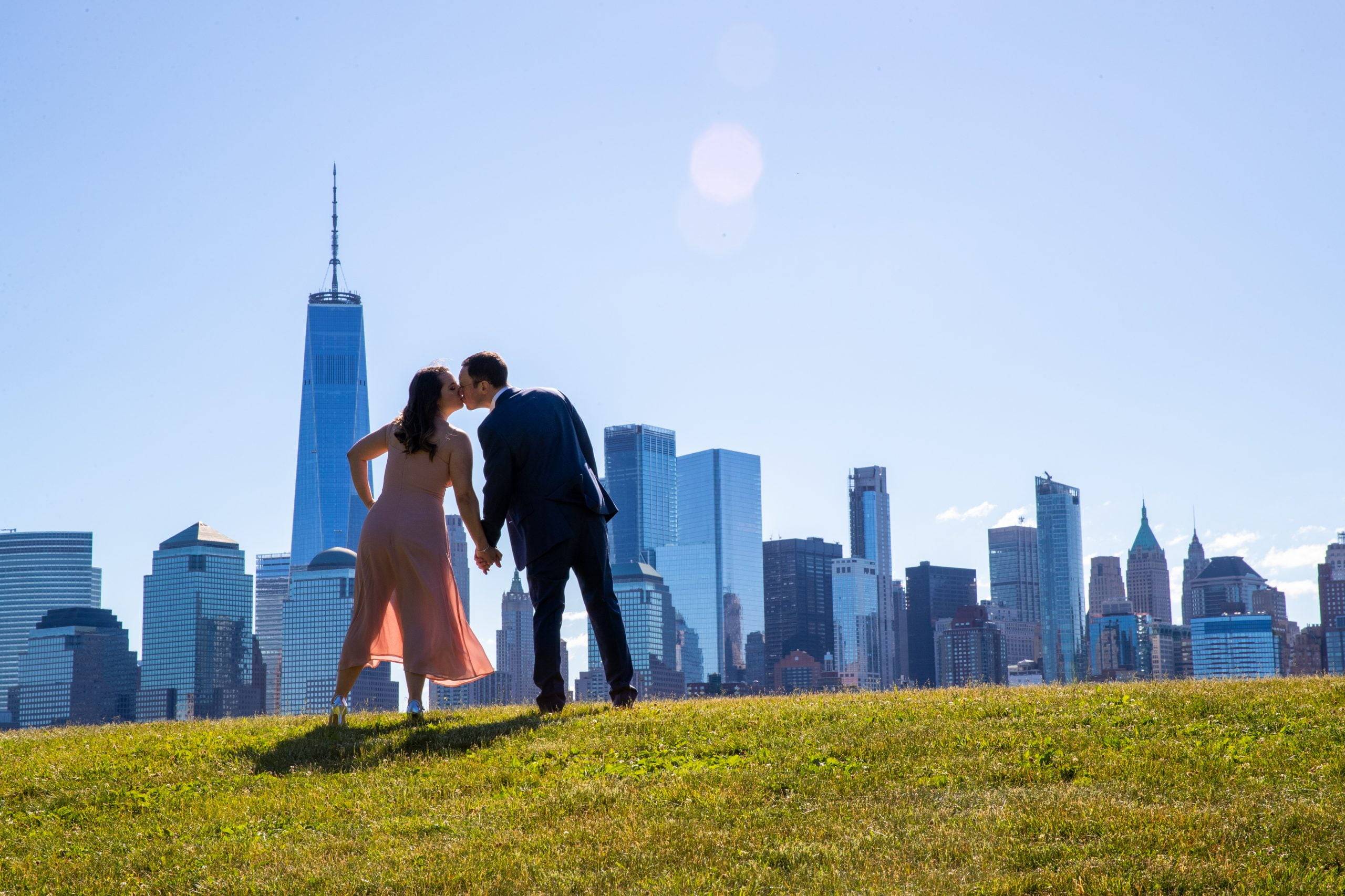 A couple kisses in front of a city skyline.