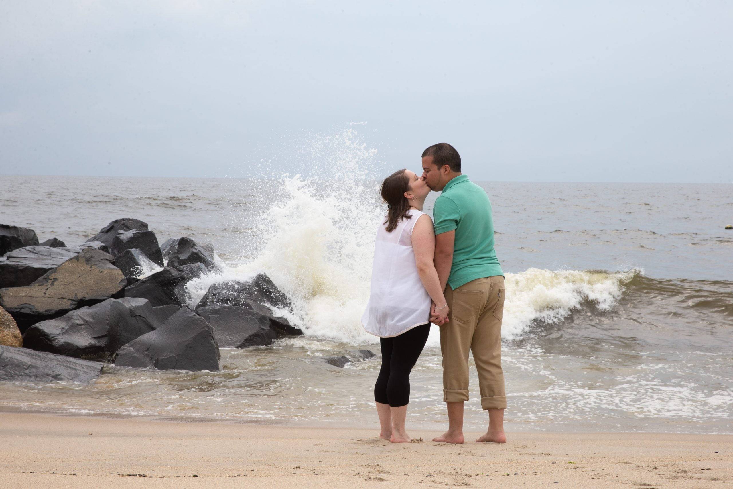 A man and a woman kissing on the beach.