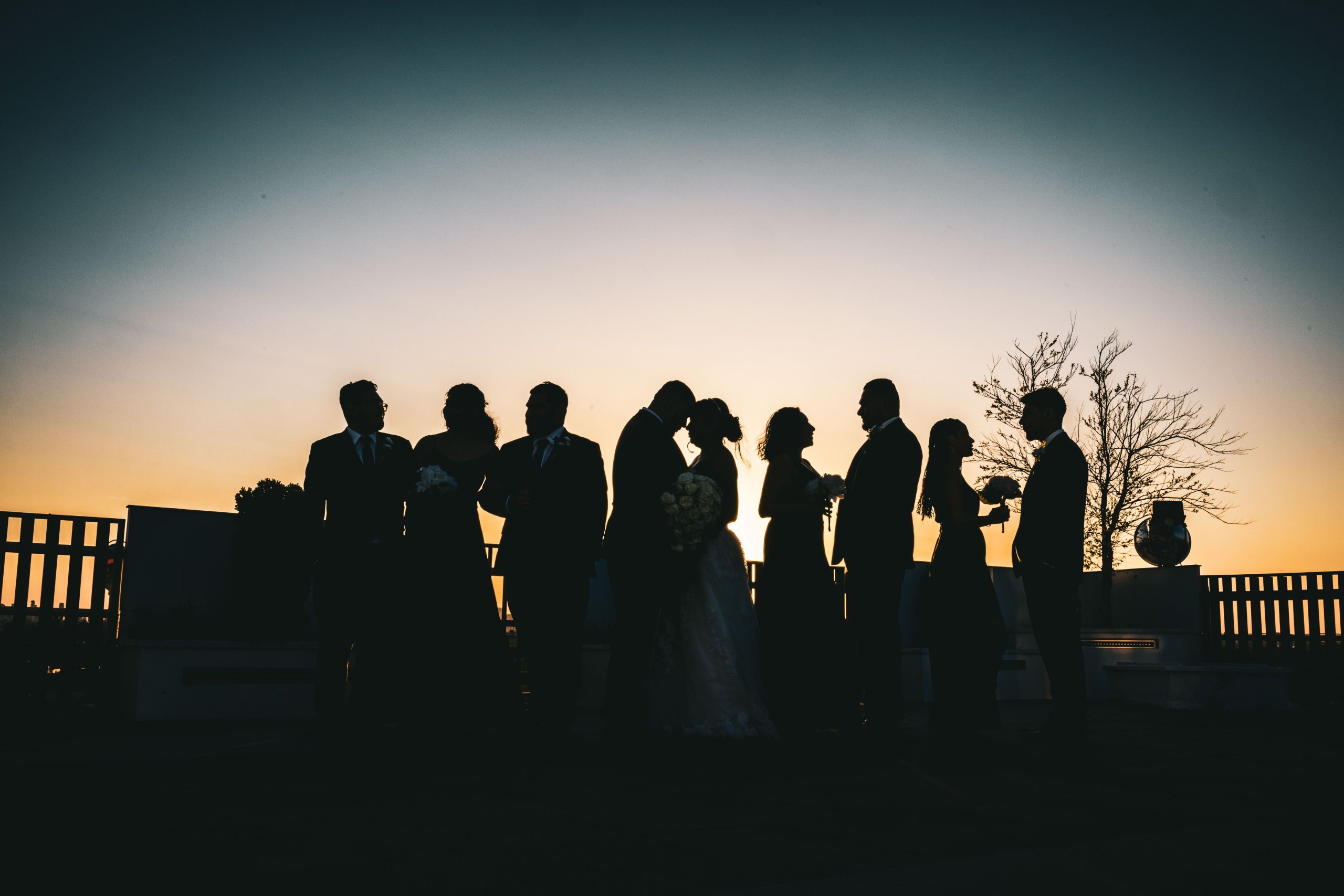 A silhouette of a wedding party in front of a sunset.