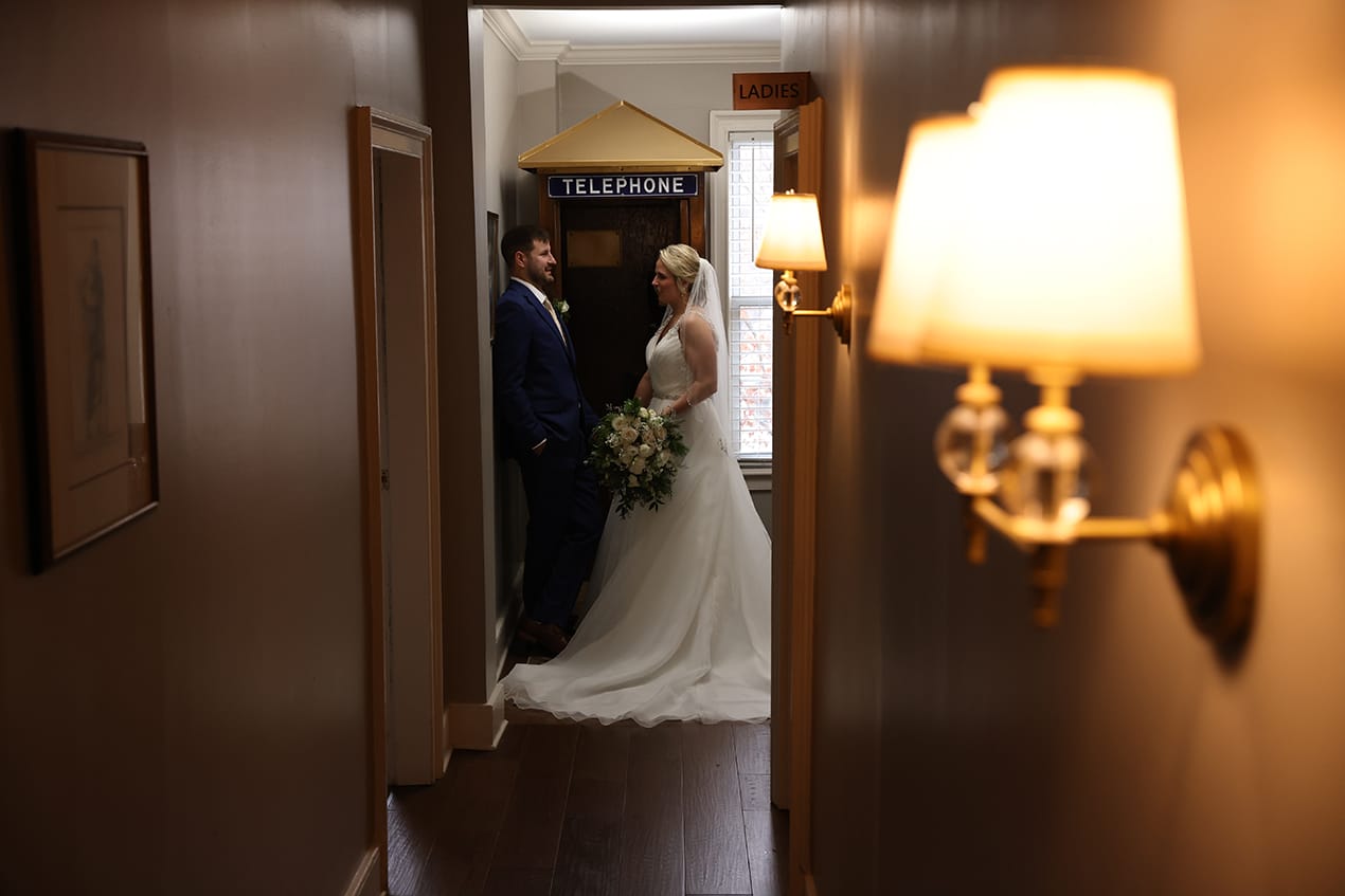 A bride and groom standing in a hallway.