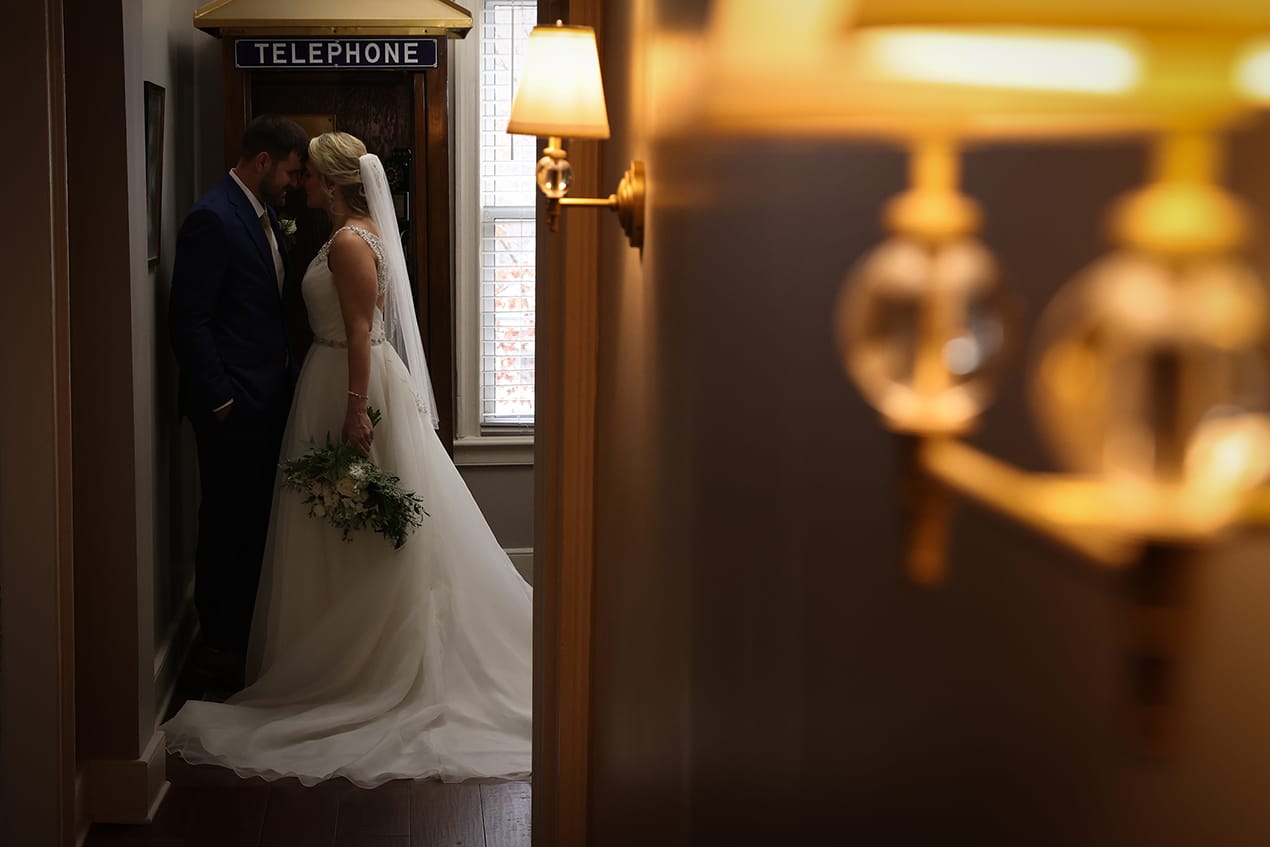 A bride and groom kissing in a hallway.