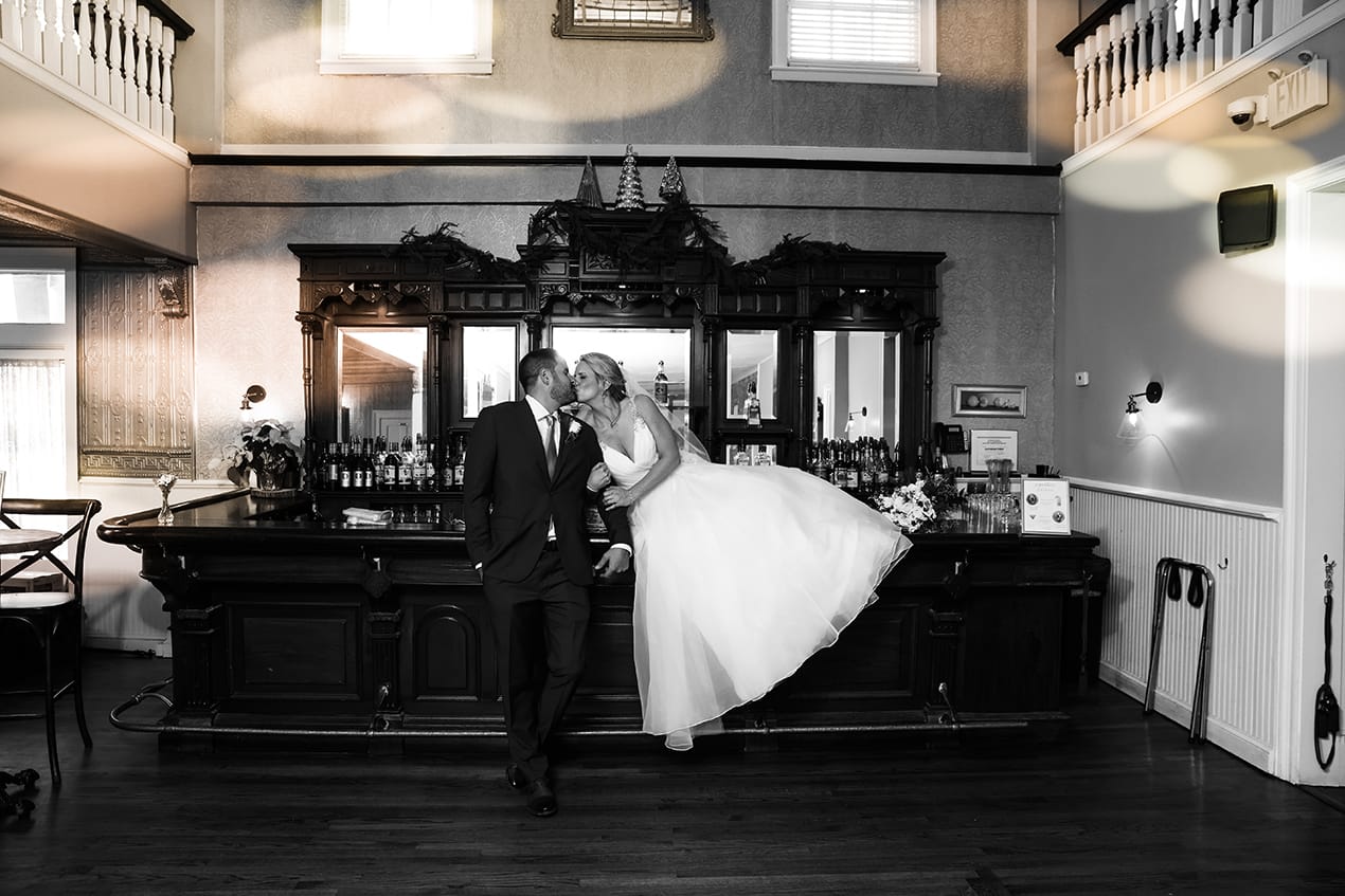 A bride and groom posing in front of a bar.