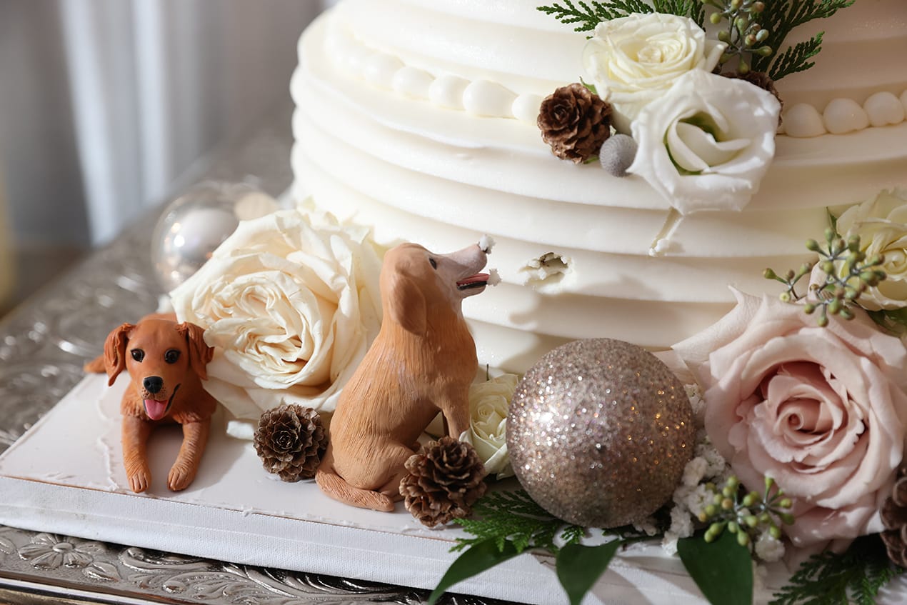 A white wedding cake with a dog figurine on top.